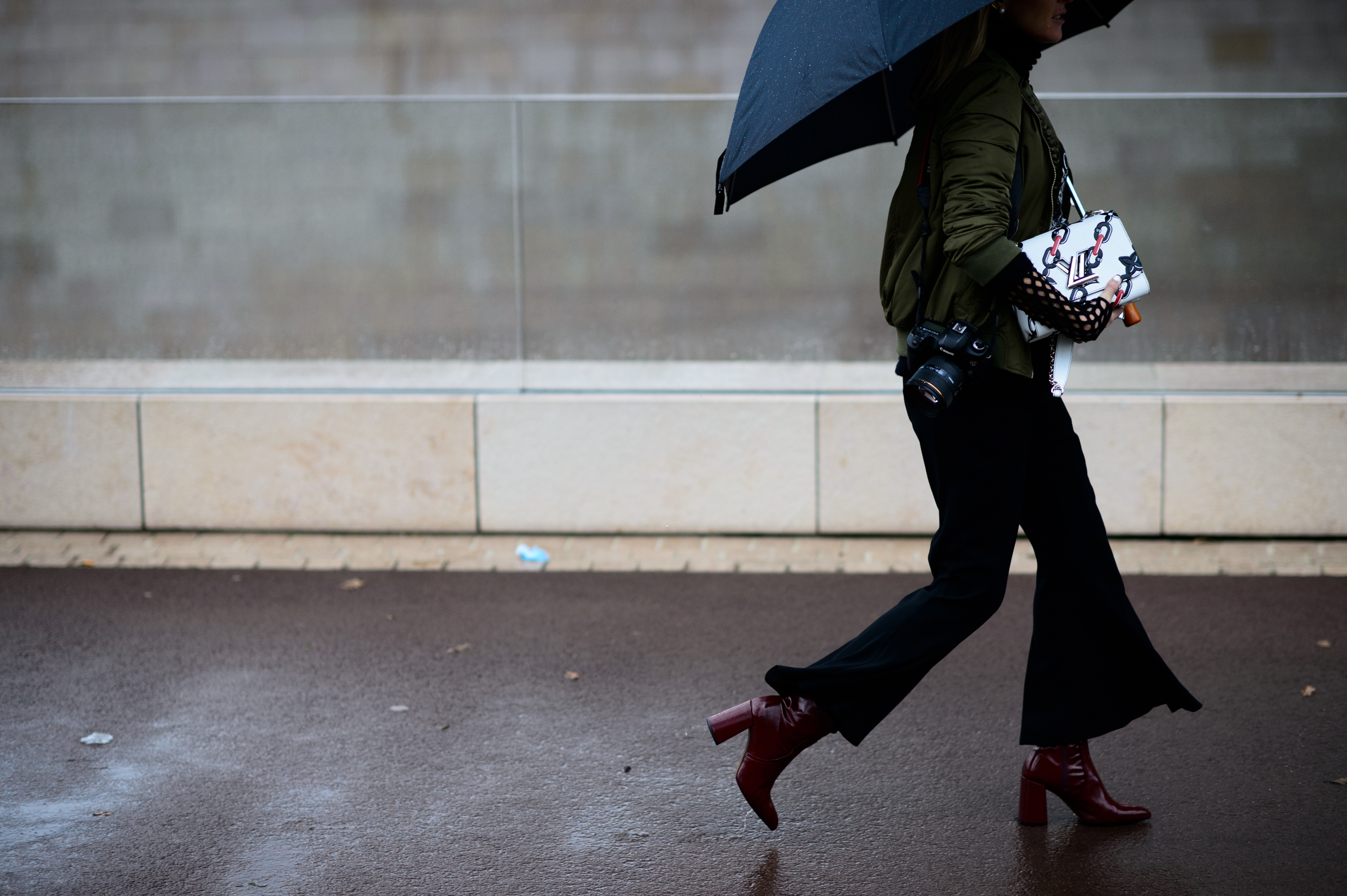 Woman walking in rain wearing green bomber jacket