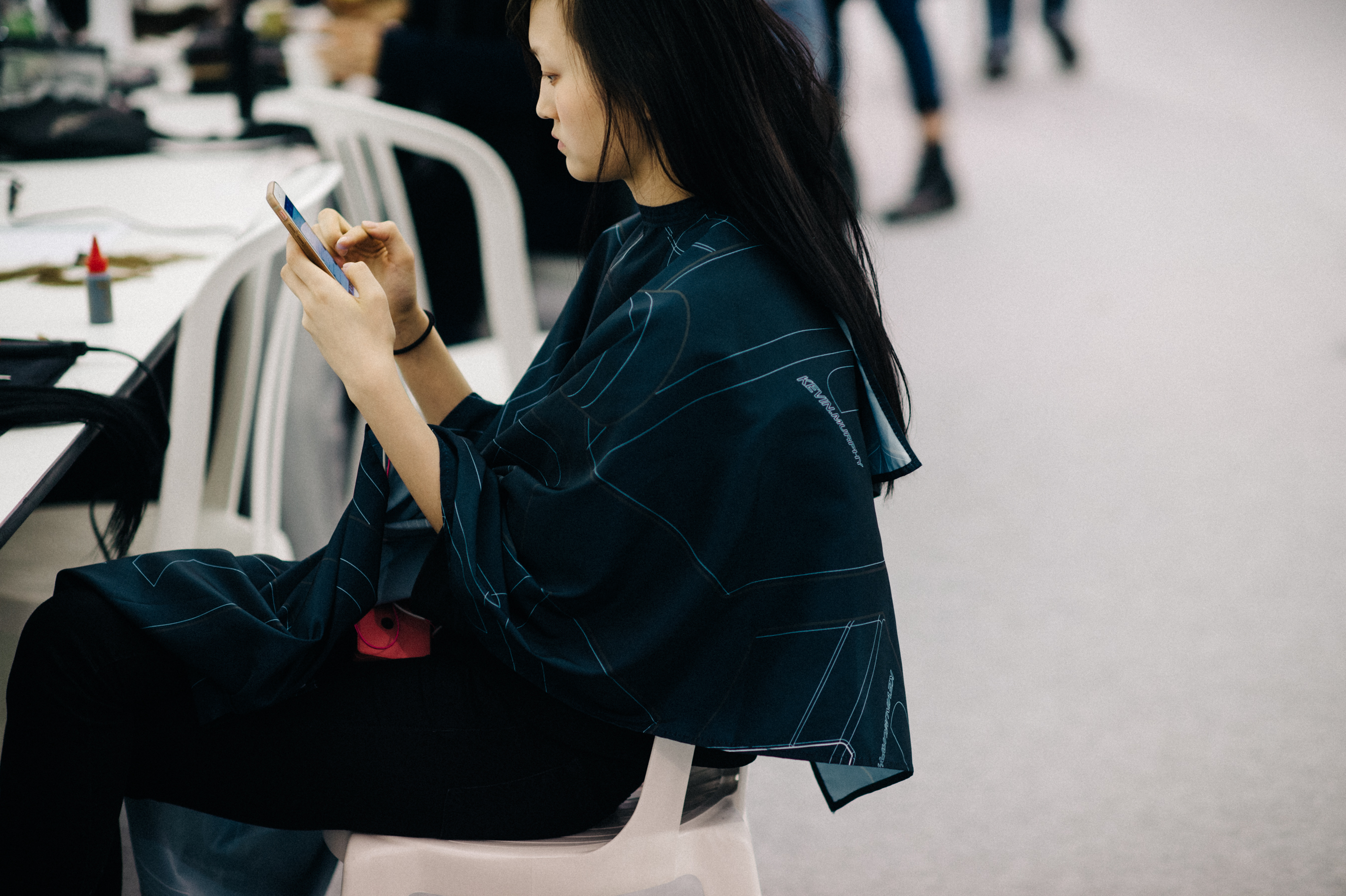 Model on phone during hair and makeup