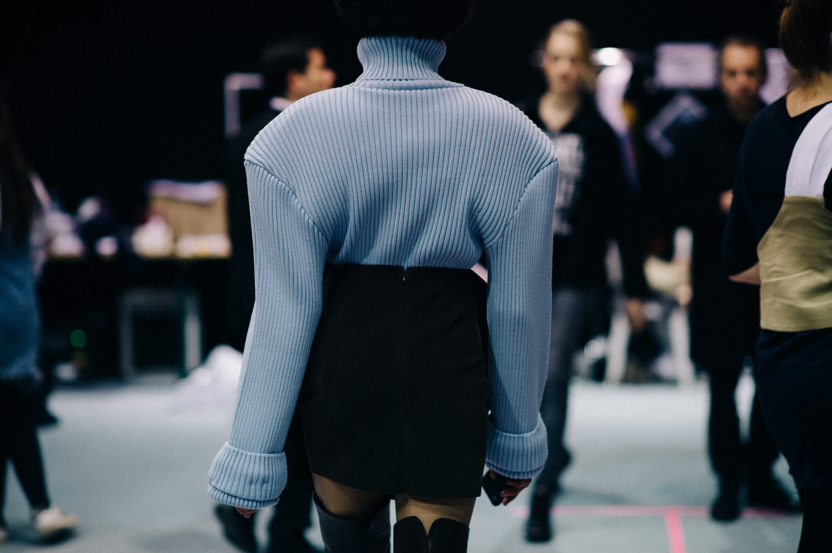 Model wears blue knit with black skirt