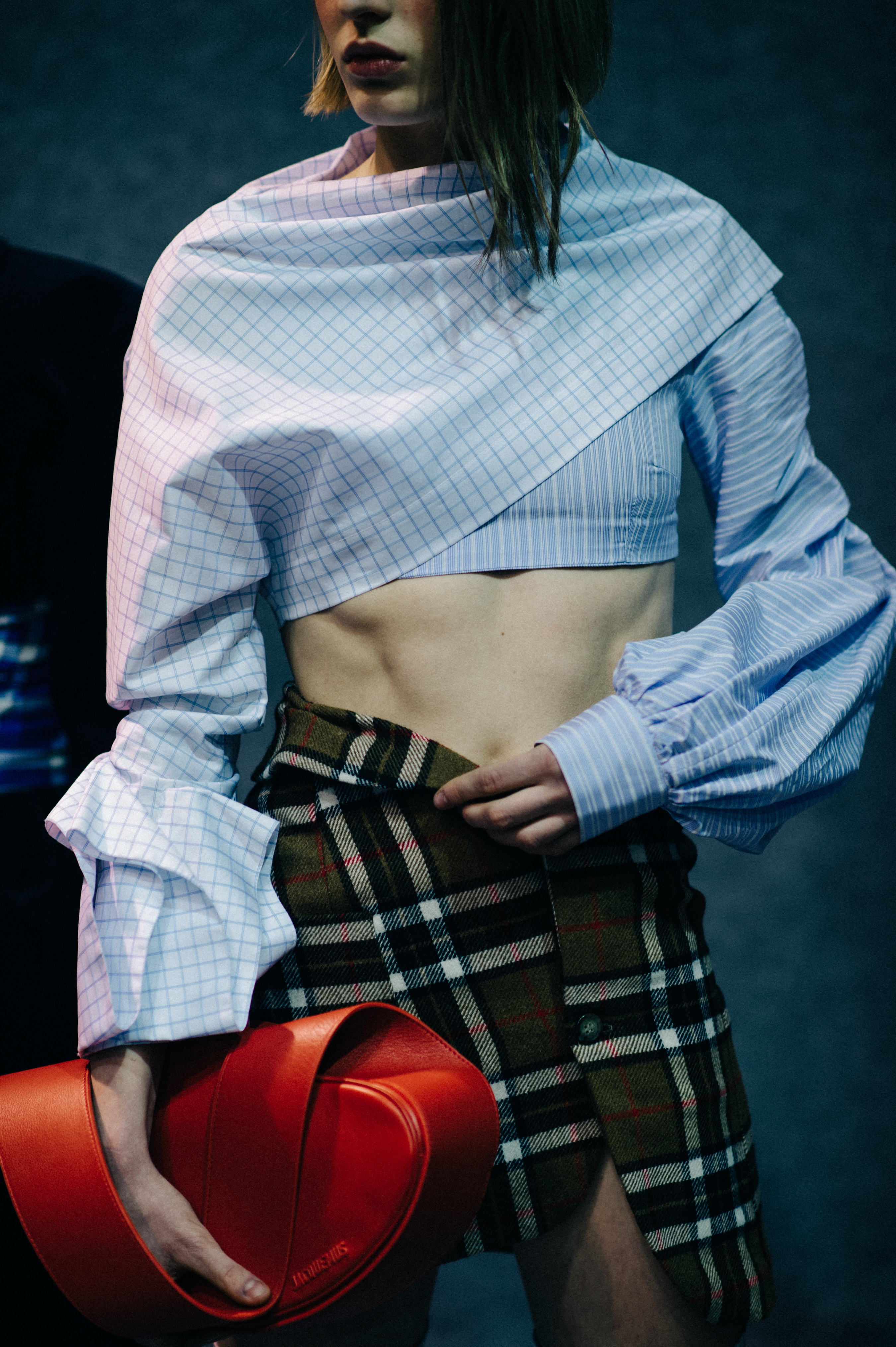 Model wearing plaid skirt with red bag