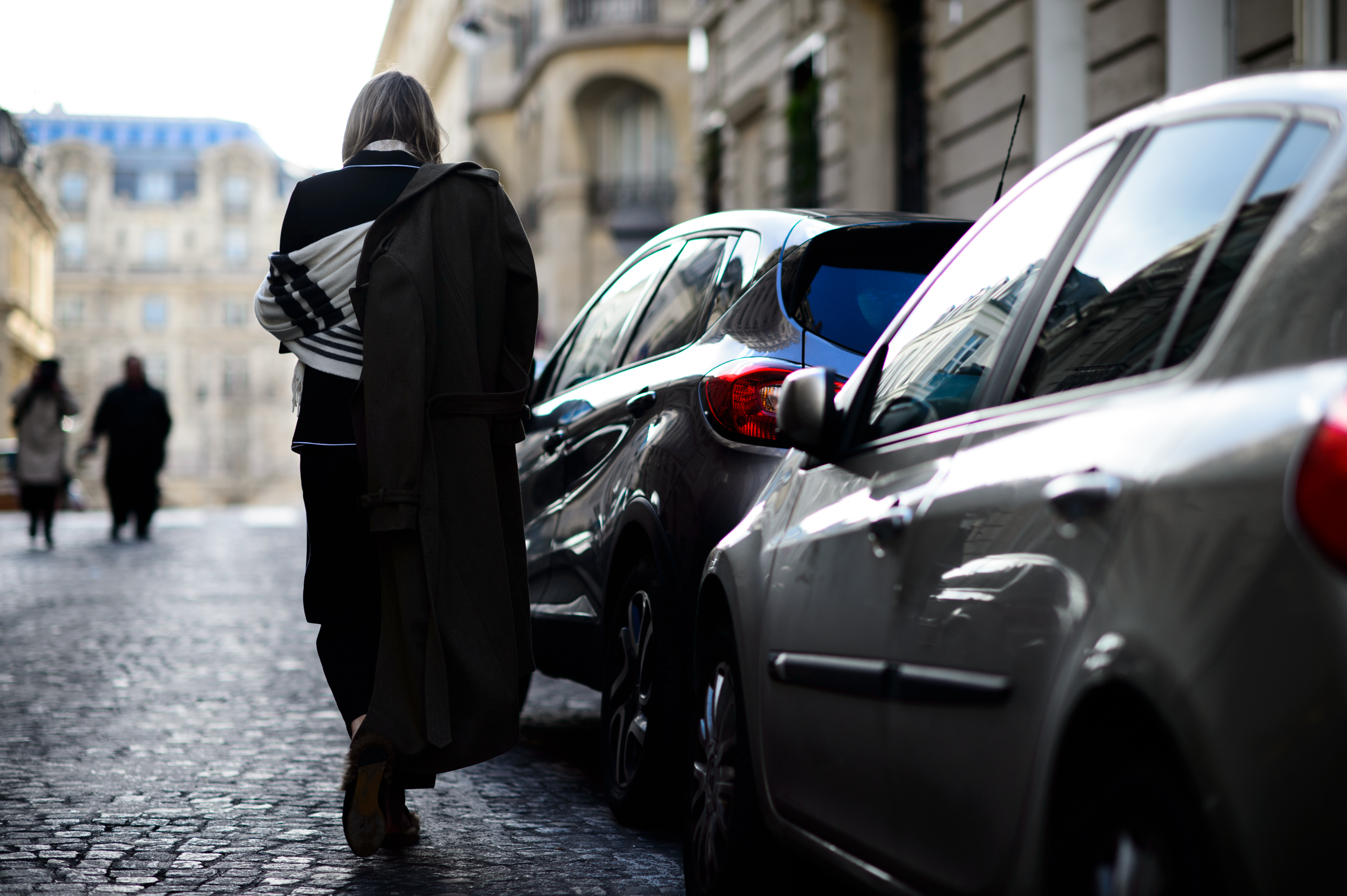 Woman wearing brown coat over one shoulder