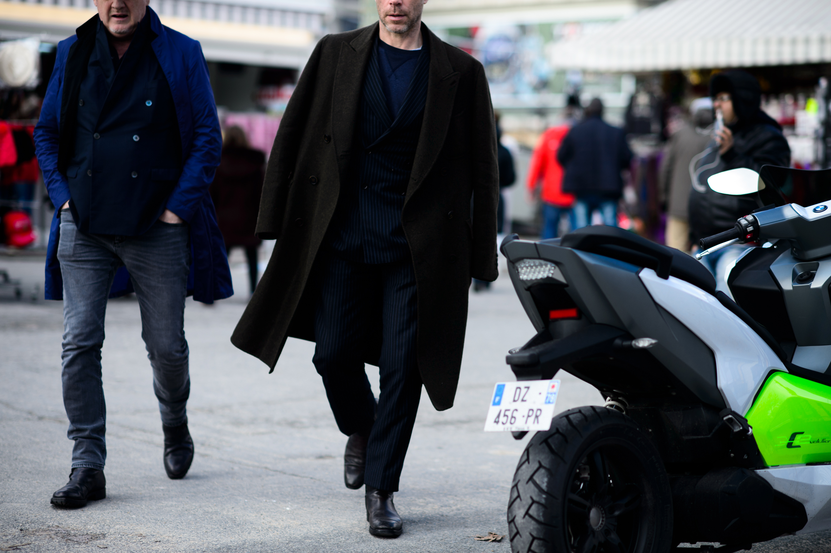 Two men wearing long coats and black shoes