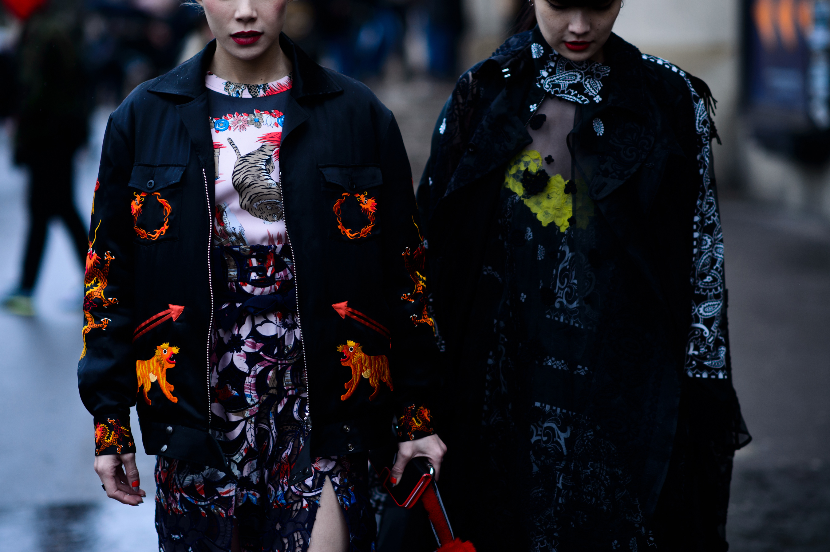 Two women walking in dark patterned outfits