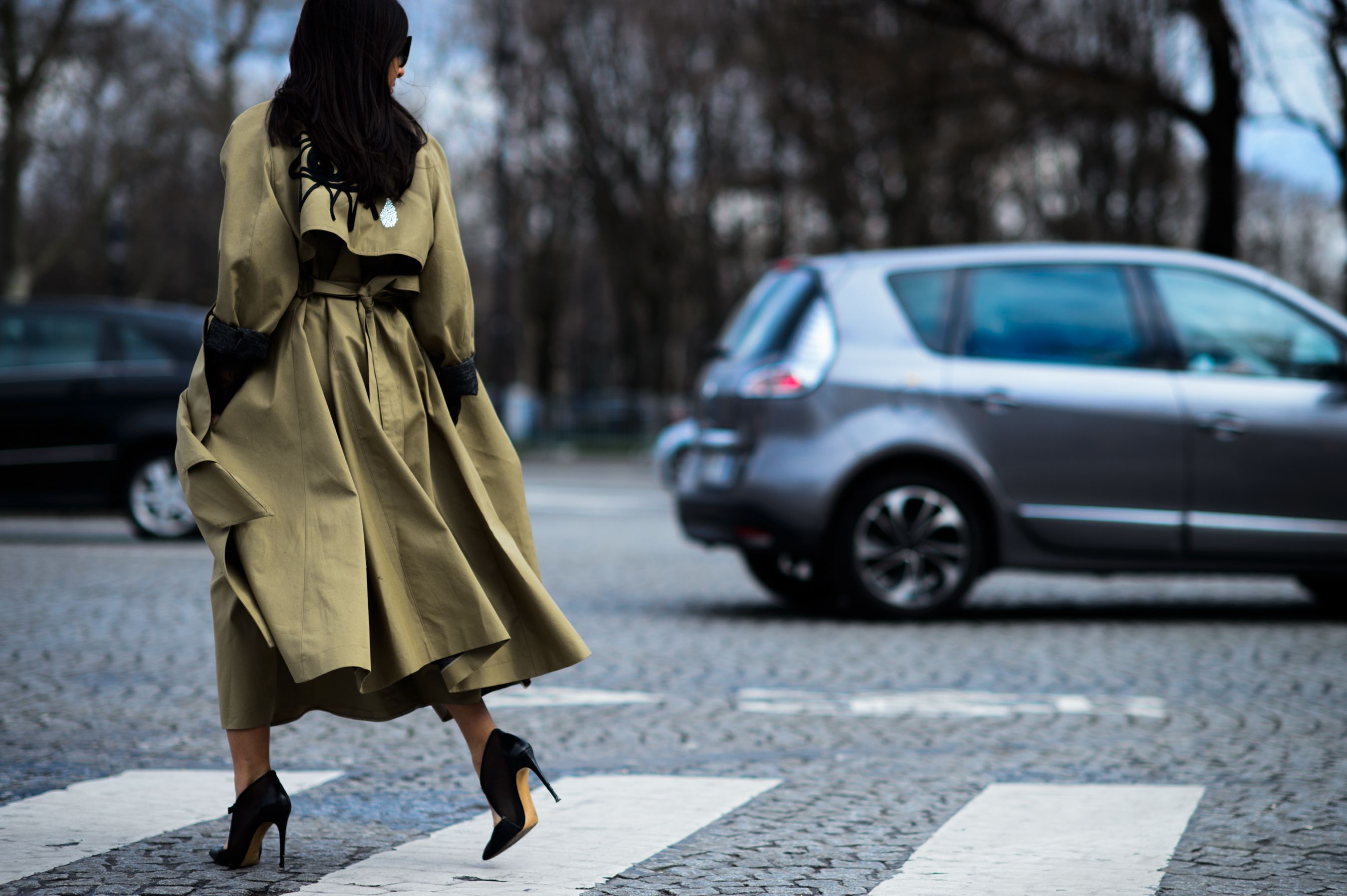 Woman crossing road in flowing trench coat