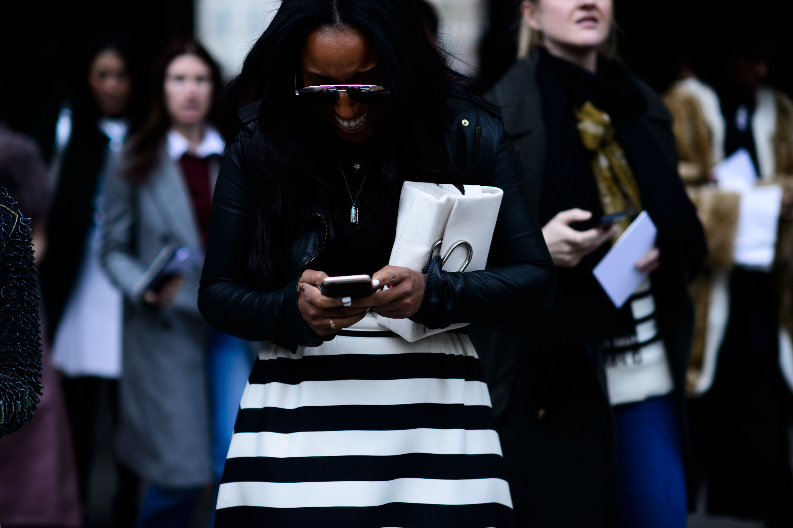 Woman smiling at phone in black and white skirt