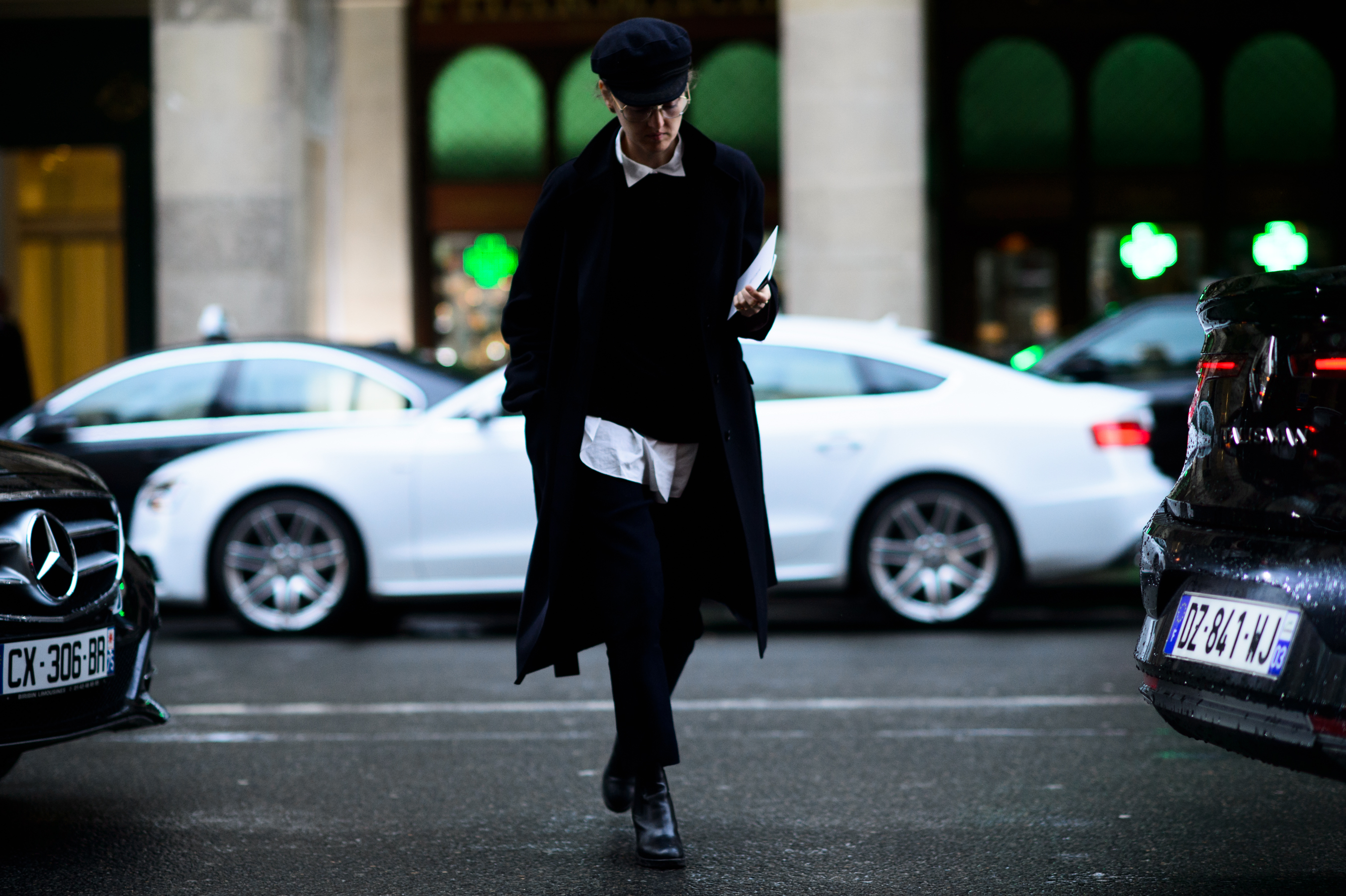 Woman wearing navy coat and hat crosses road
