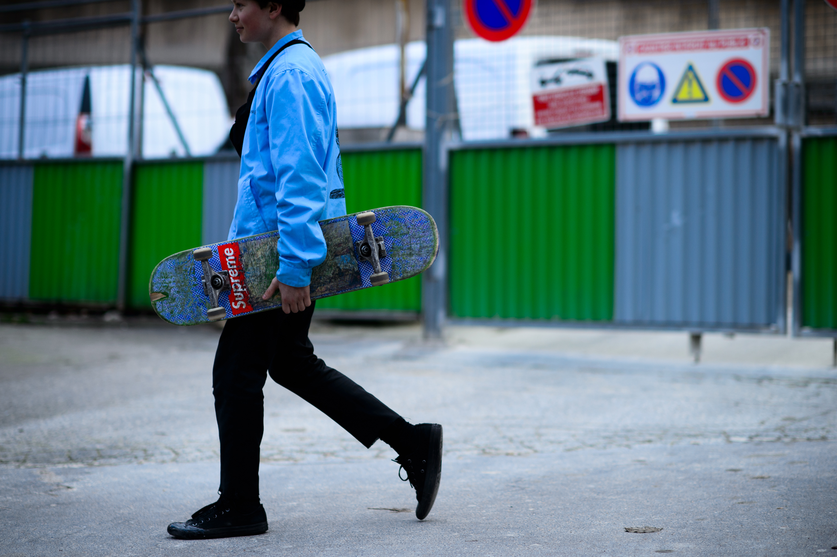 Man walking in blue jacket with skateboard