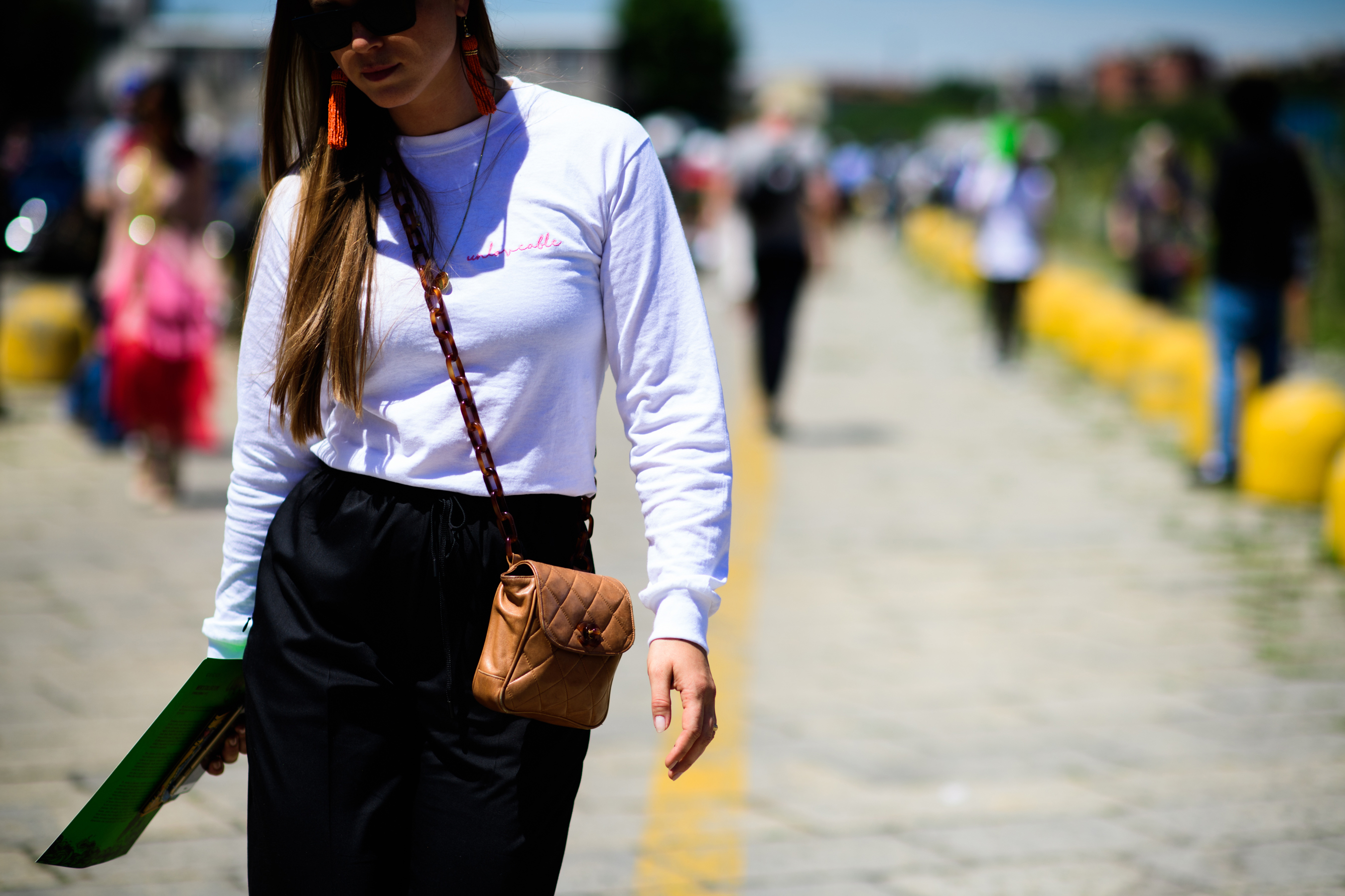 A woman in a white top with a beige bag