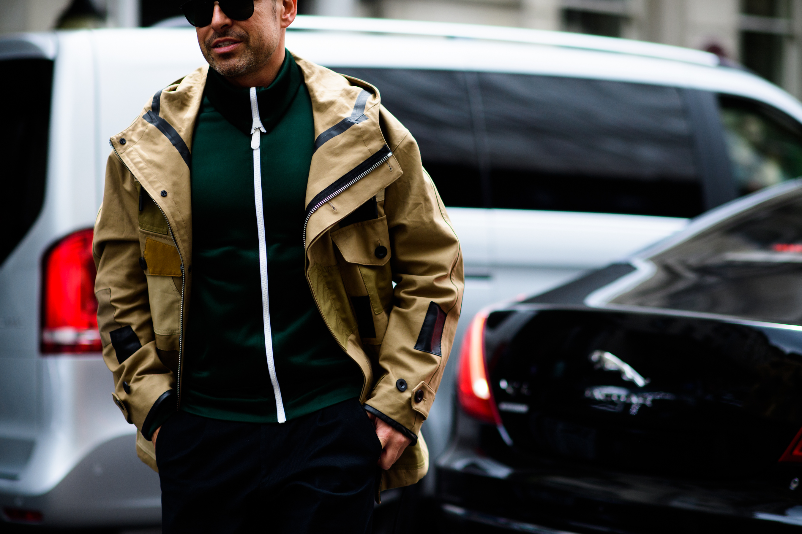A man wearing beige raincoat, sunglasses