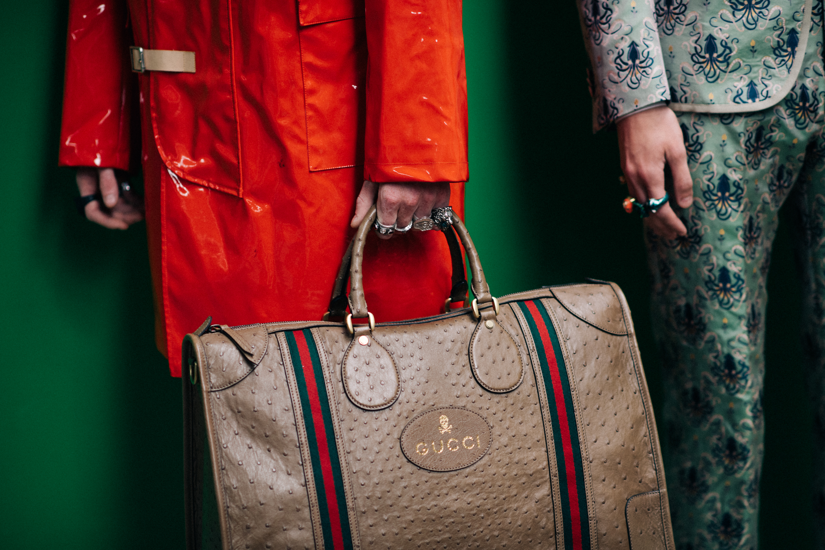 A model in an orange coat with a bag