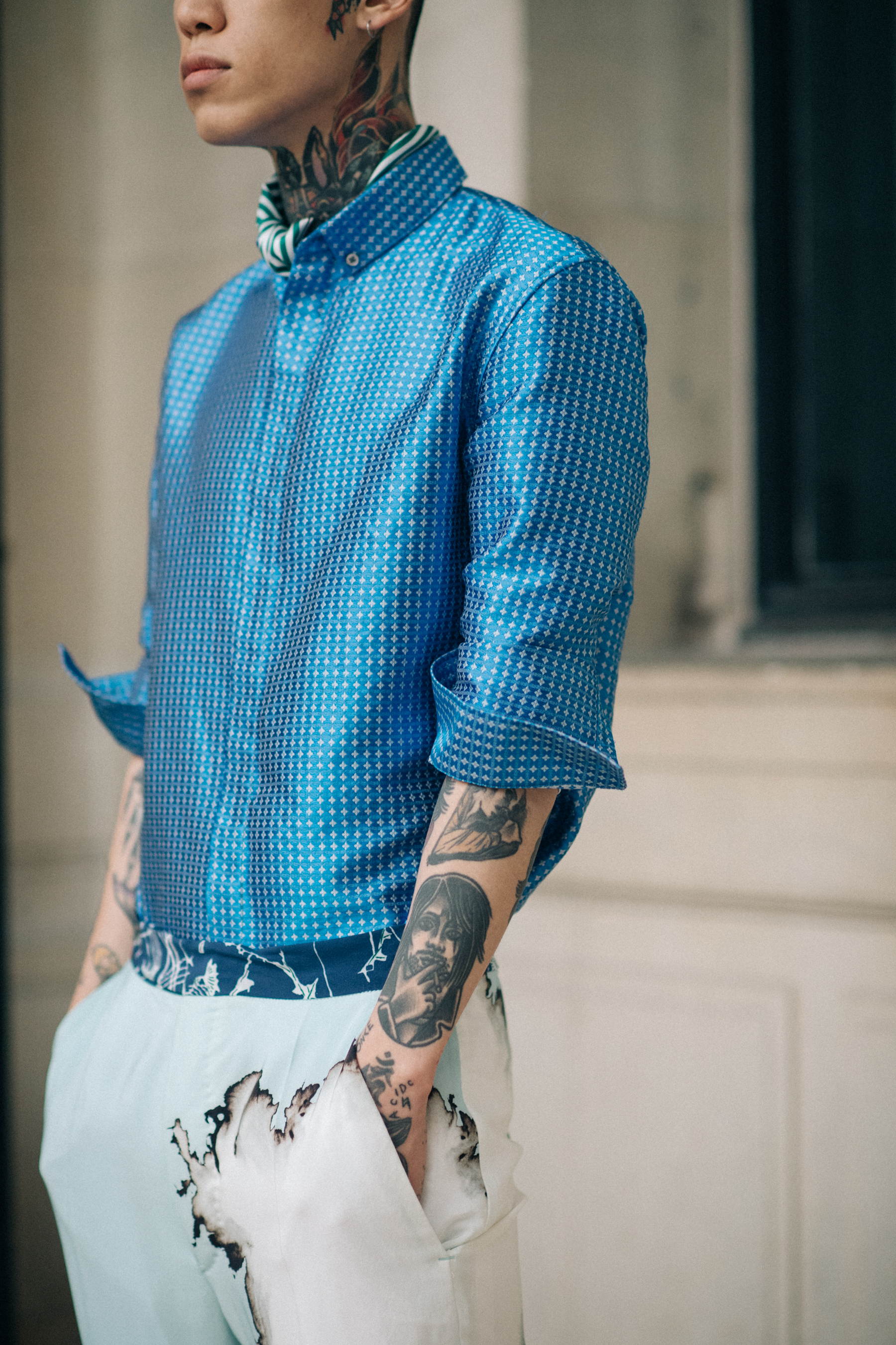 A model in a blue shirt and white trousers