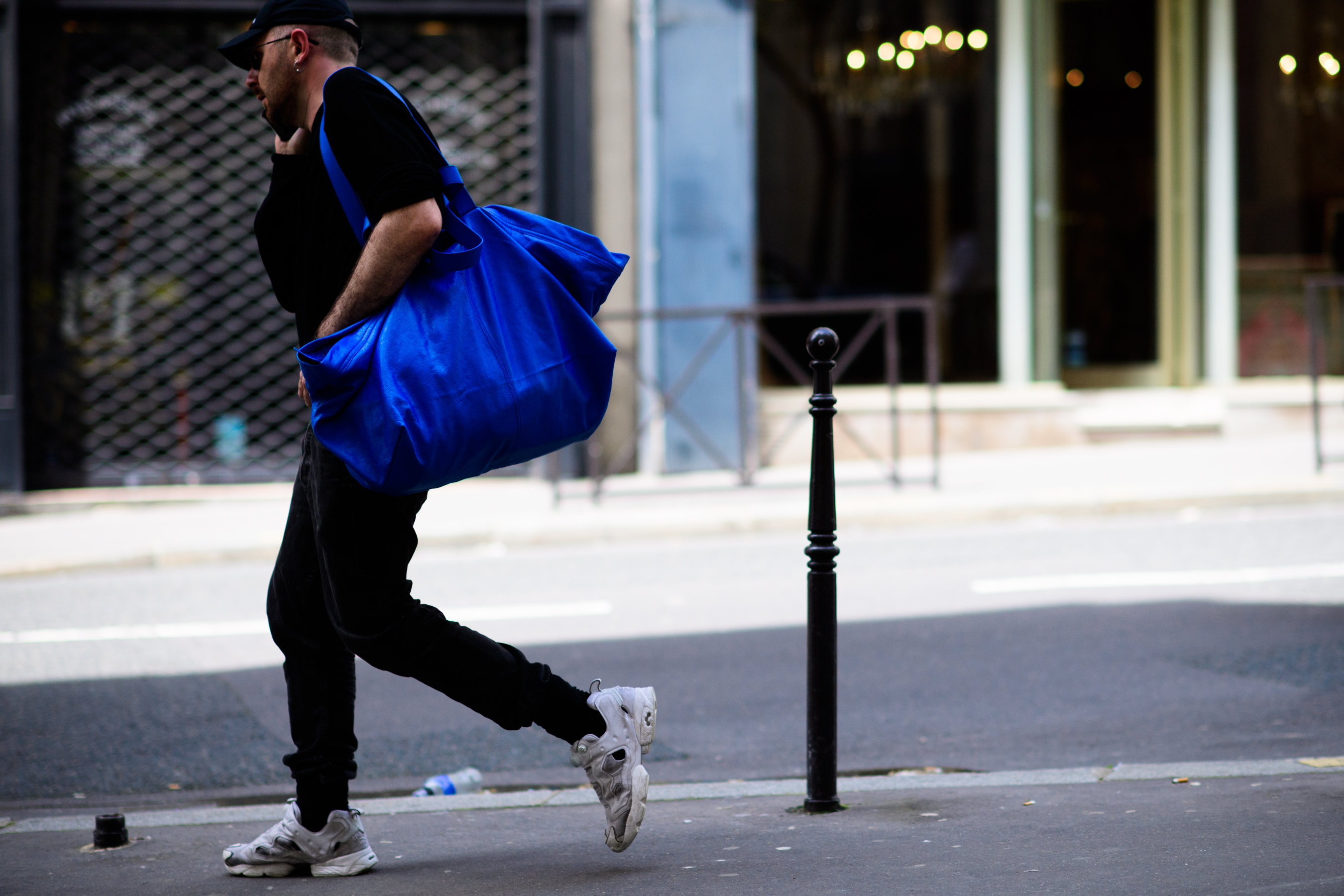 A man walking with a blue bag