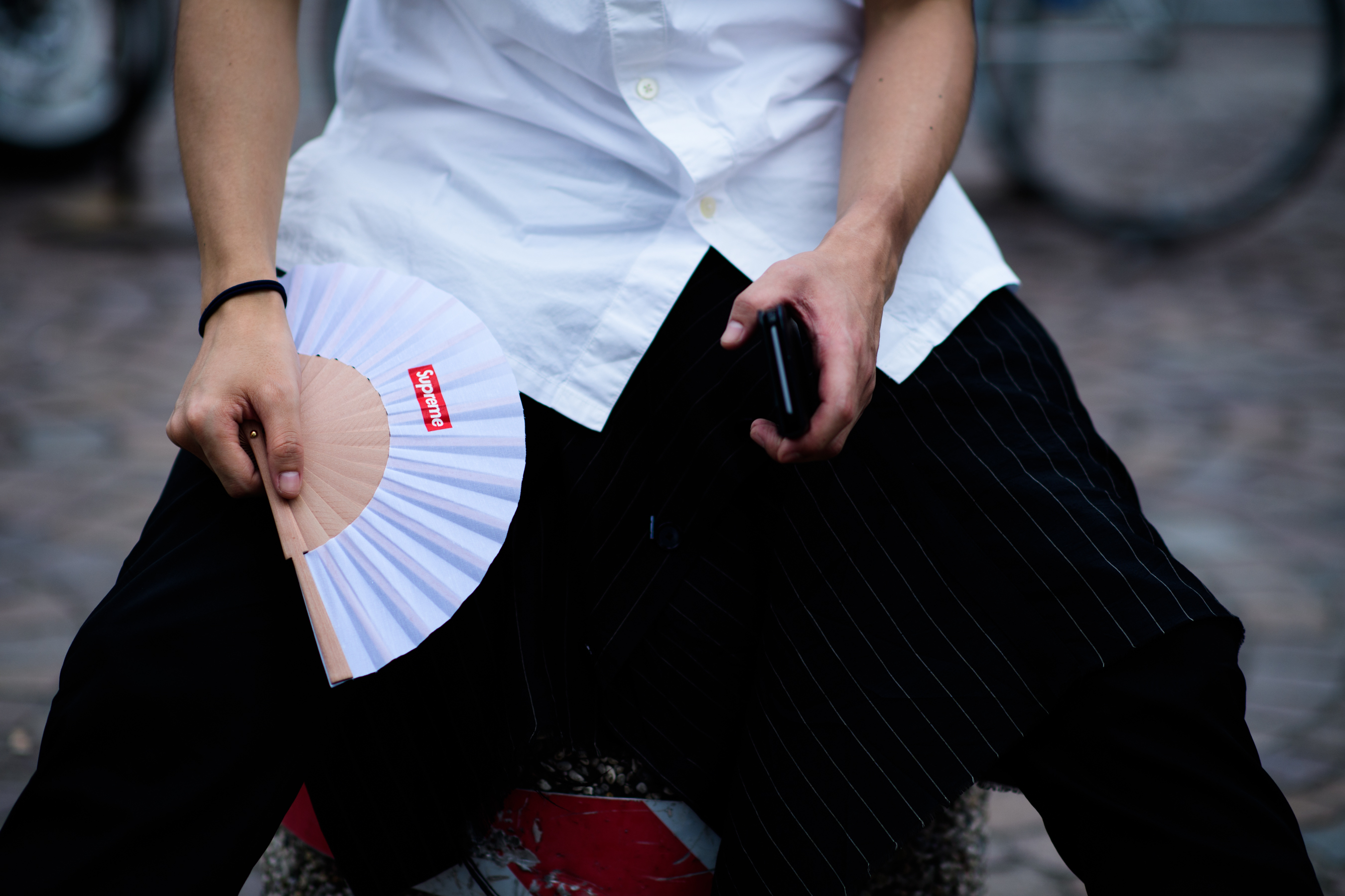 Hands holding a phone and a fan