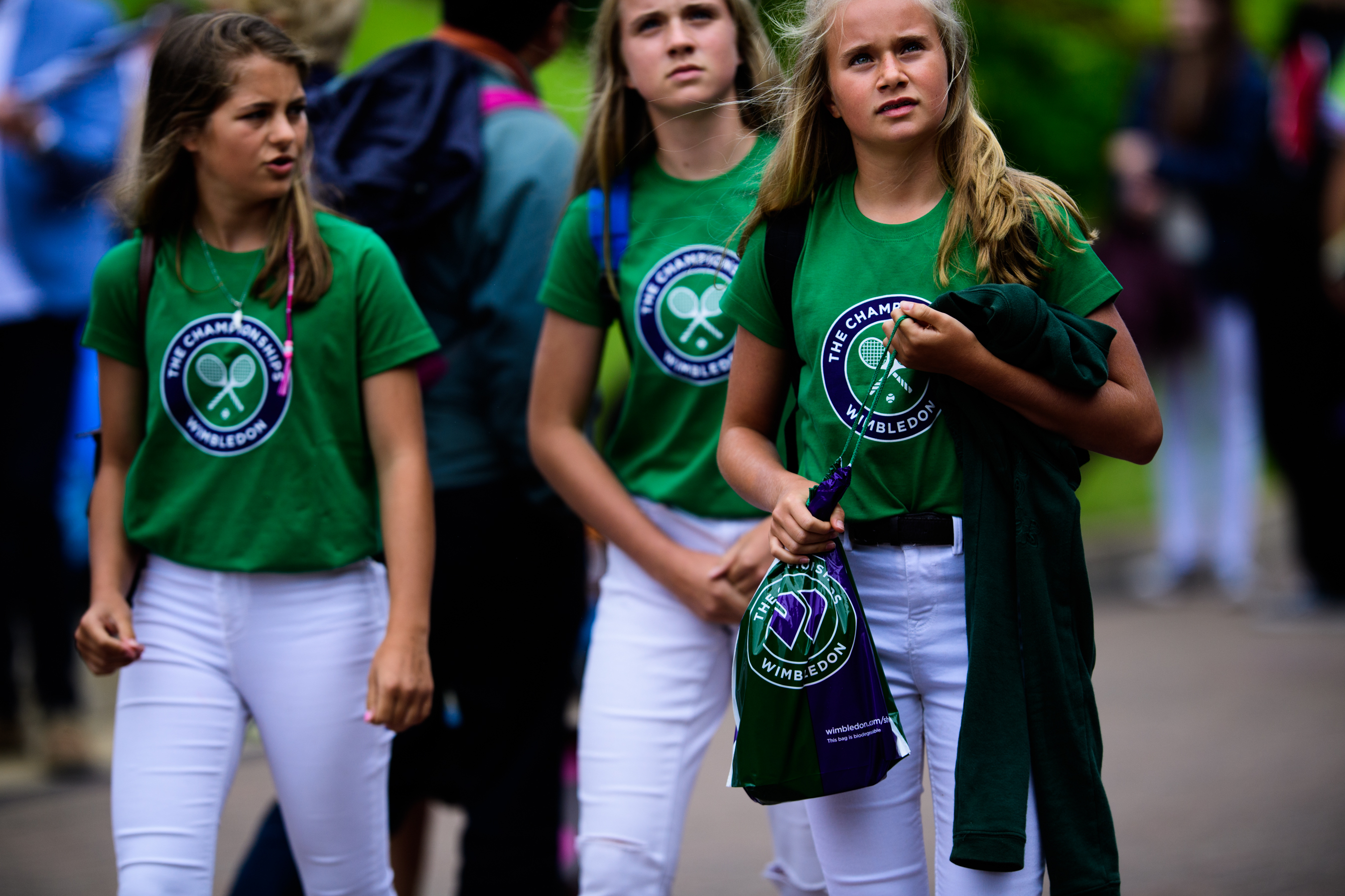 Three girls wearing green logo t-shirts