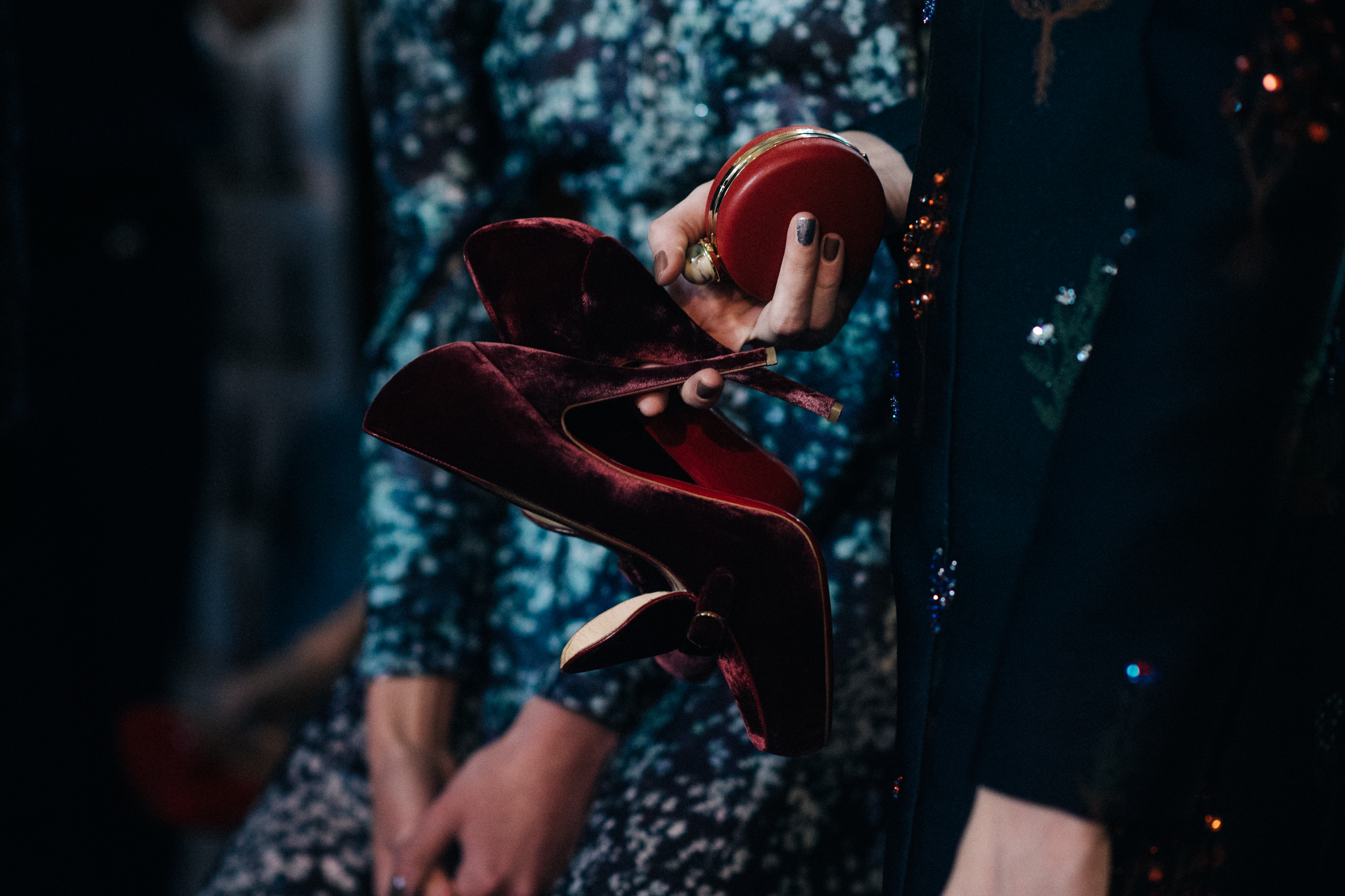 Model holding Christian Louboutin velvet shoes