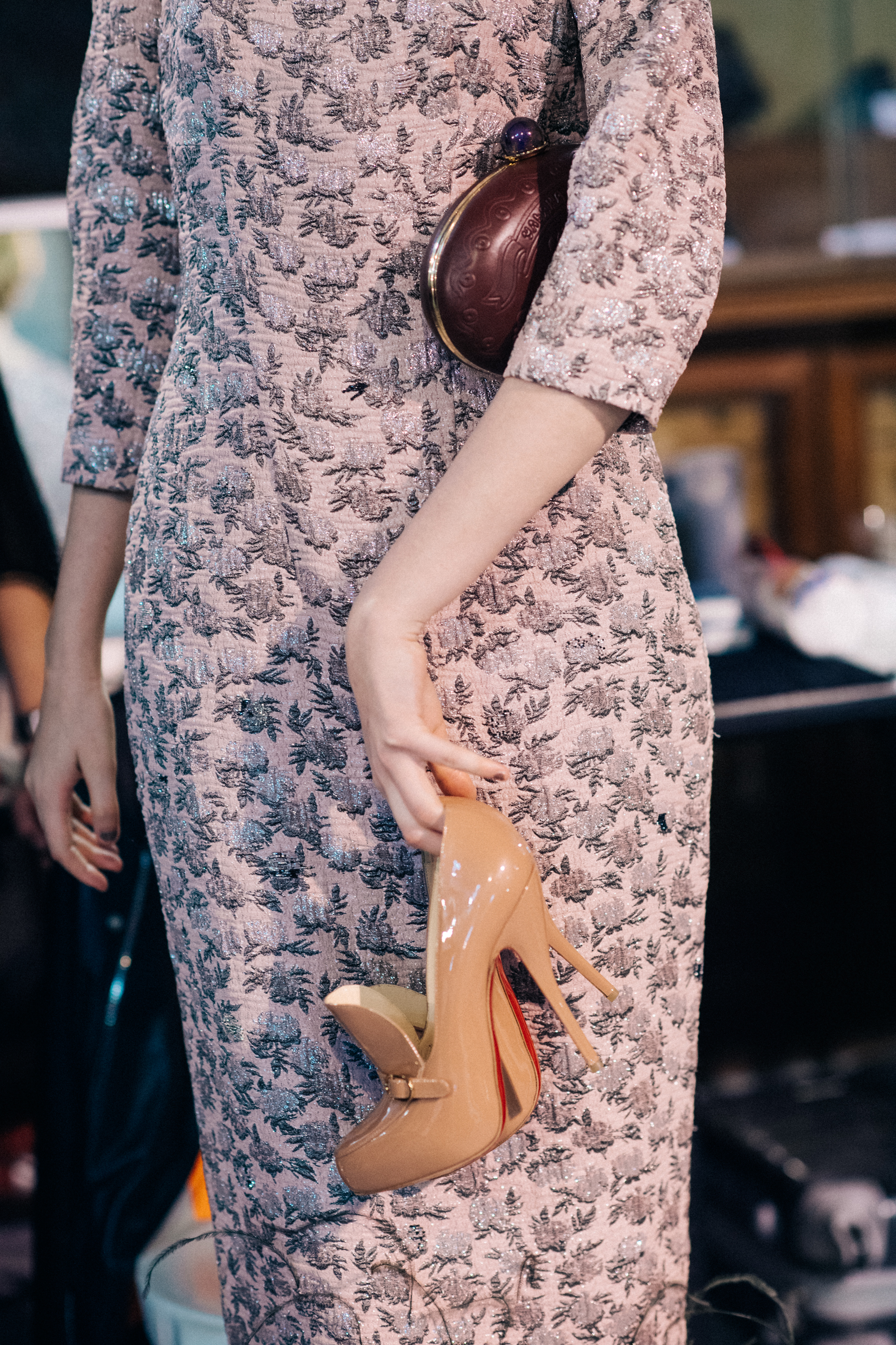 Model holding Christian Louboutin beige shoes