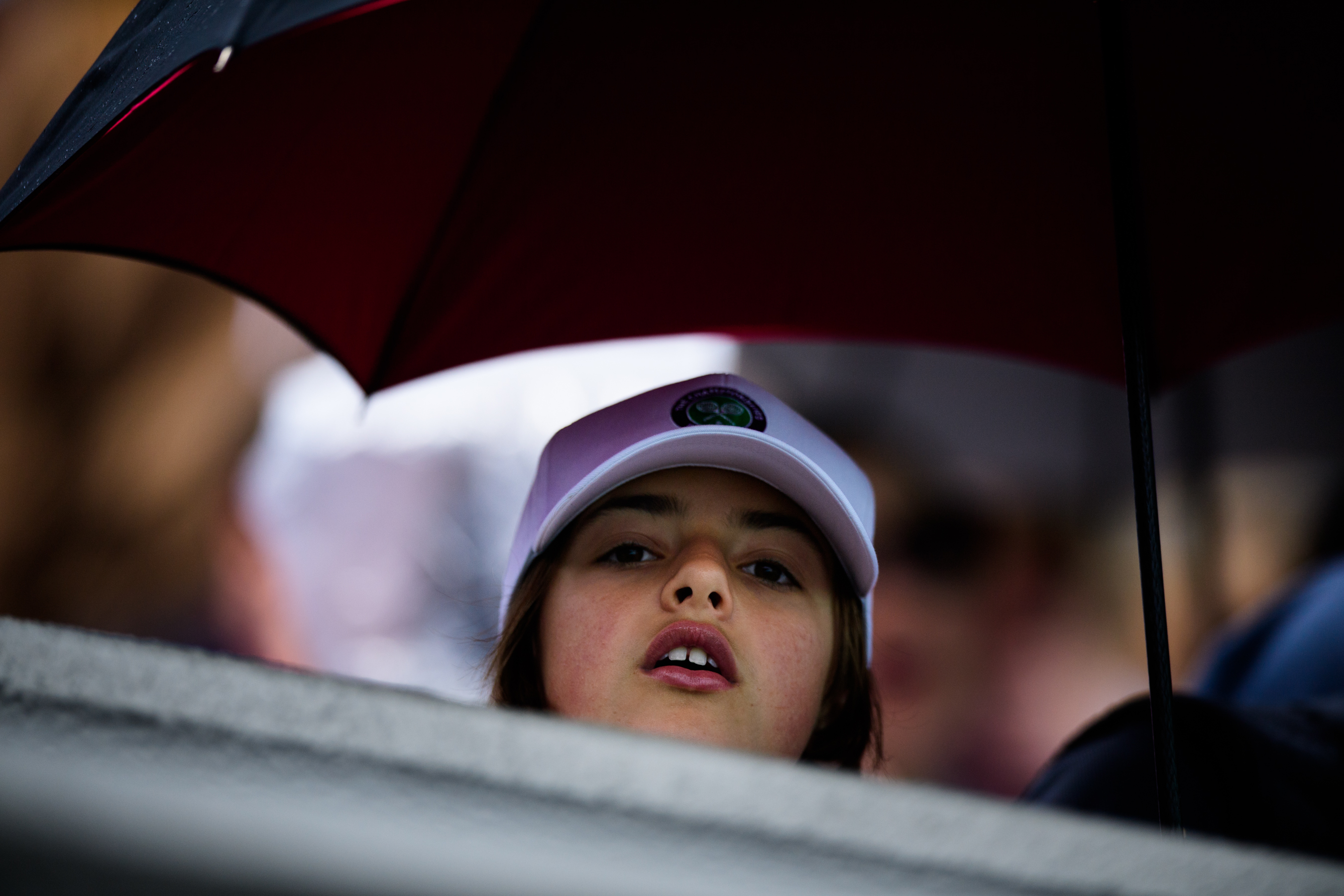 Child wearing big hat watching tennis