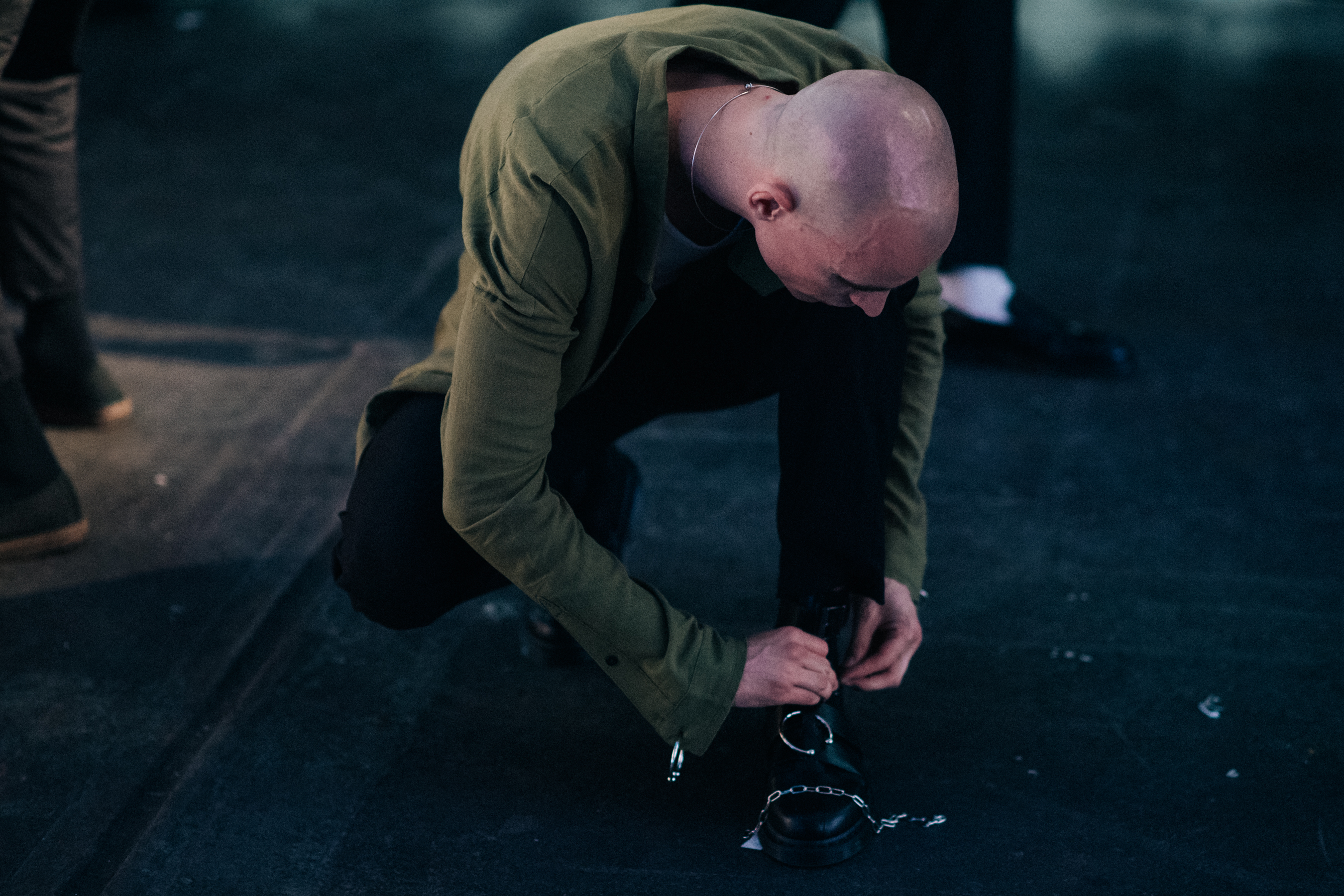 Shaved head male model fixing shoe