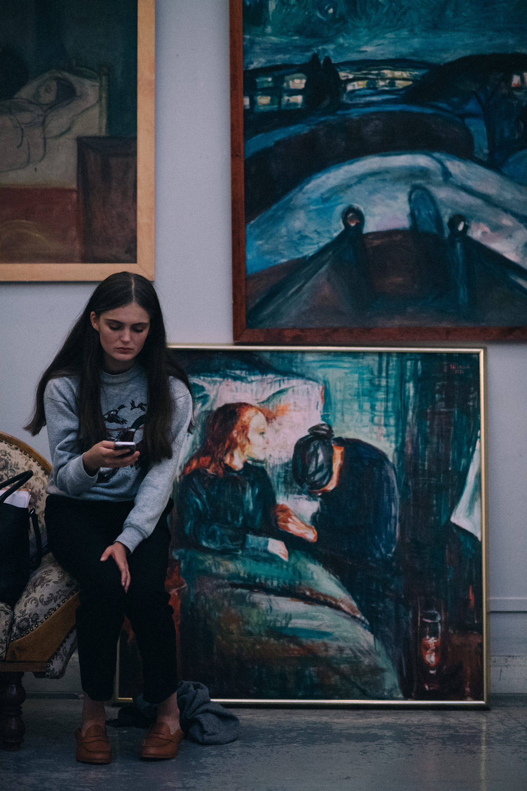 Model sitting next to wall with paintings