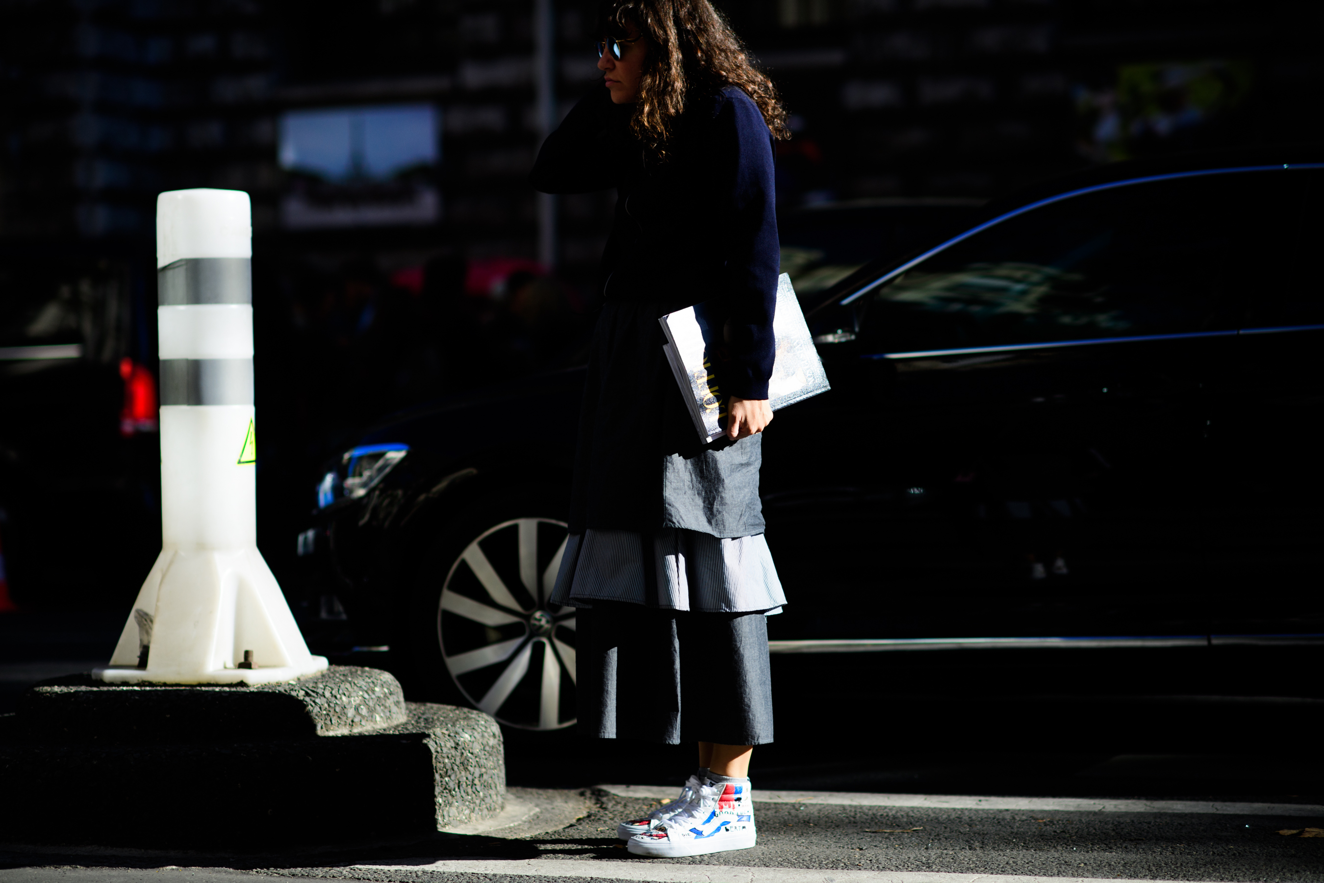 Woman standing in harsh light and grey skirt