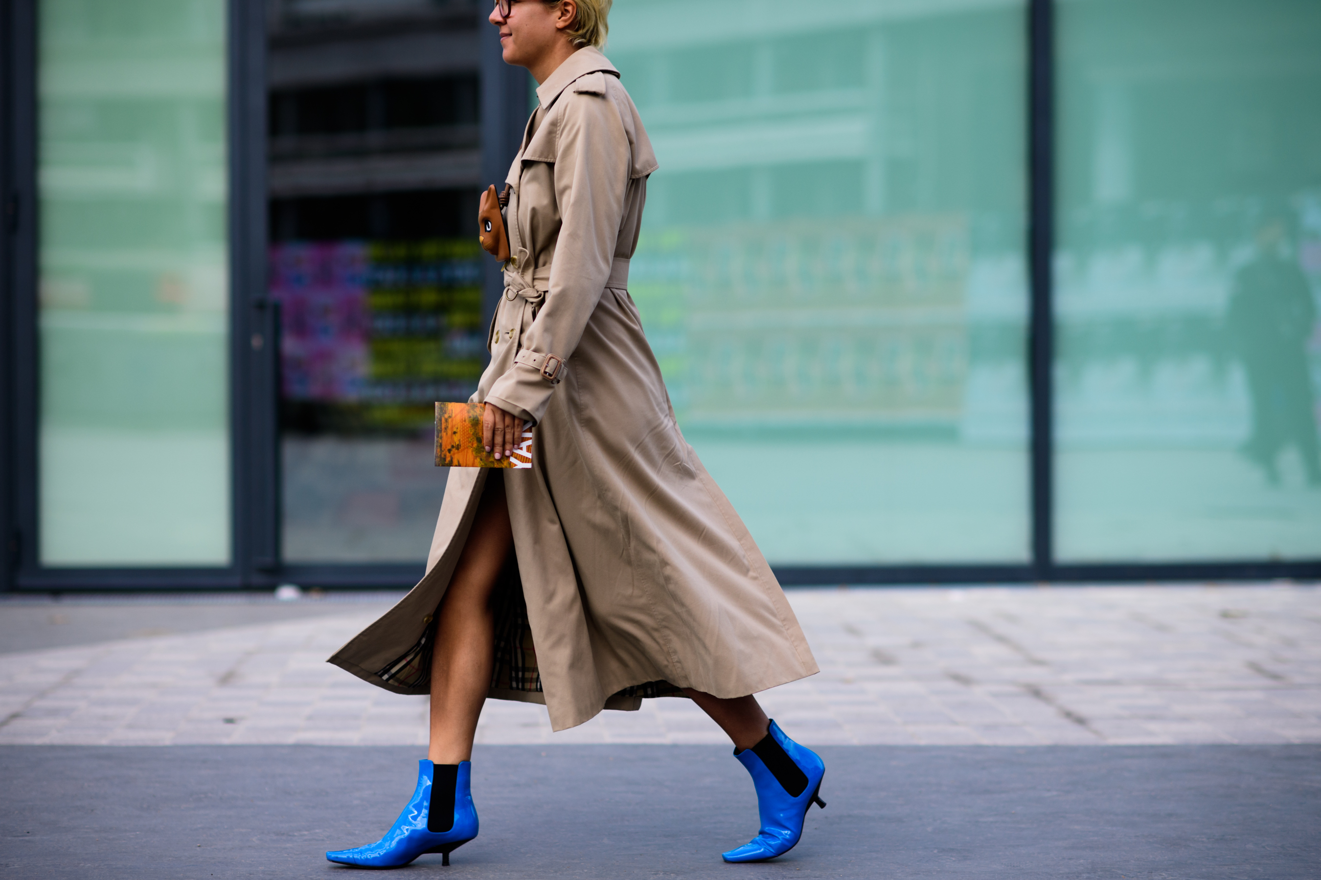 Woman walking in blue shoes and camel trench coat