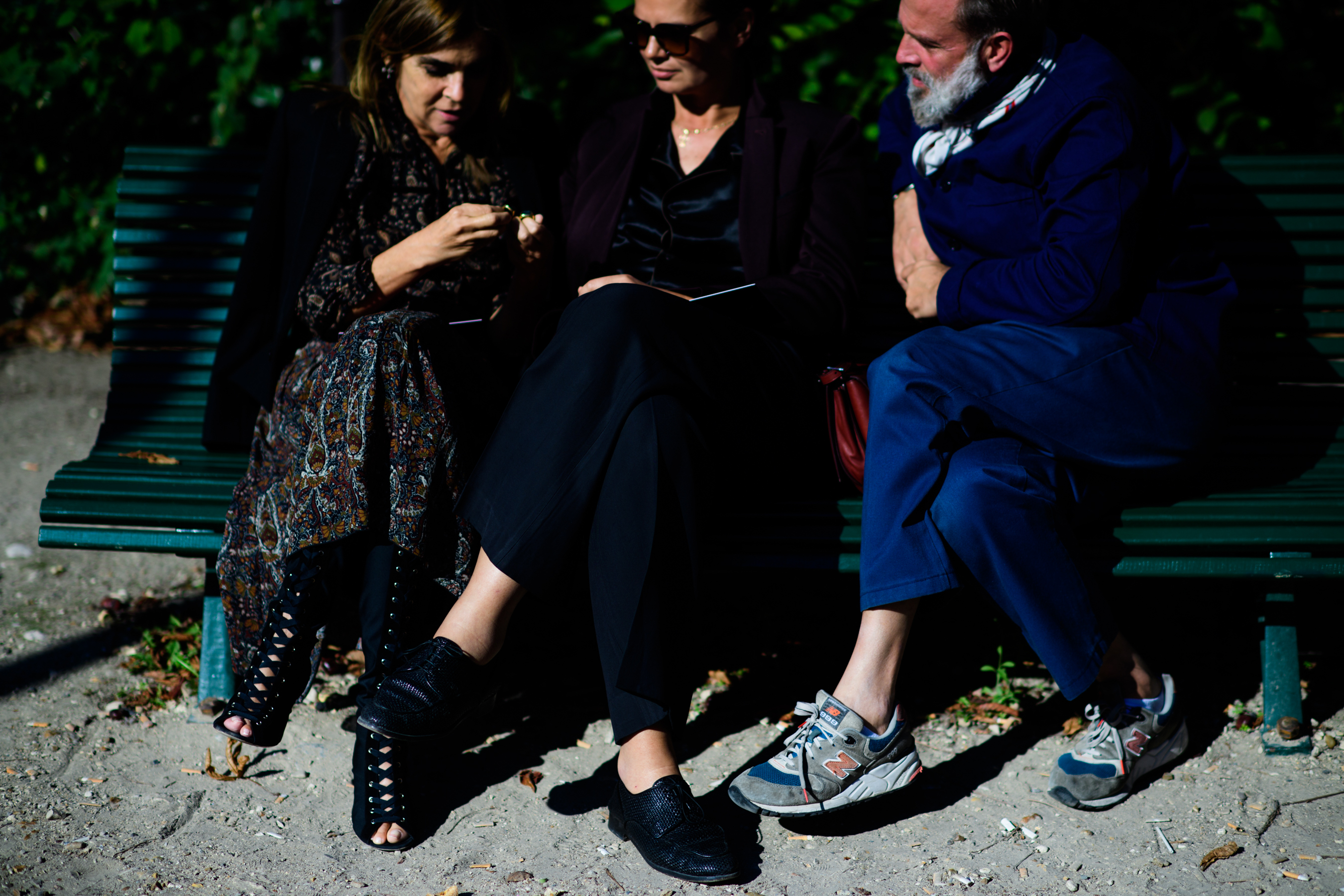Three people sat on green bench before show