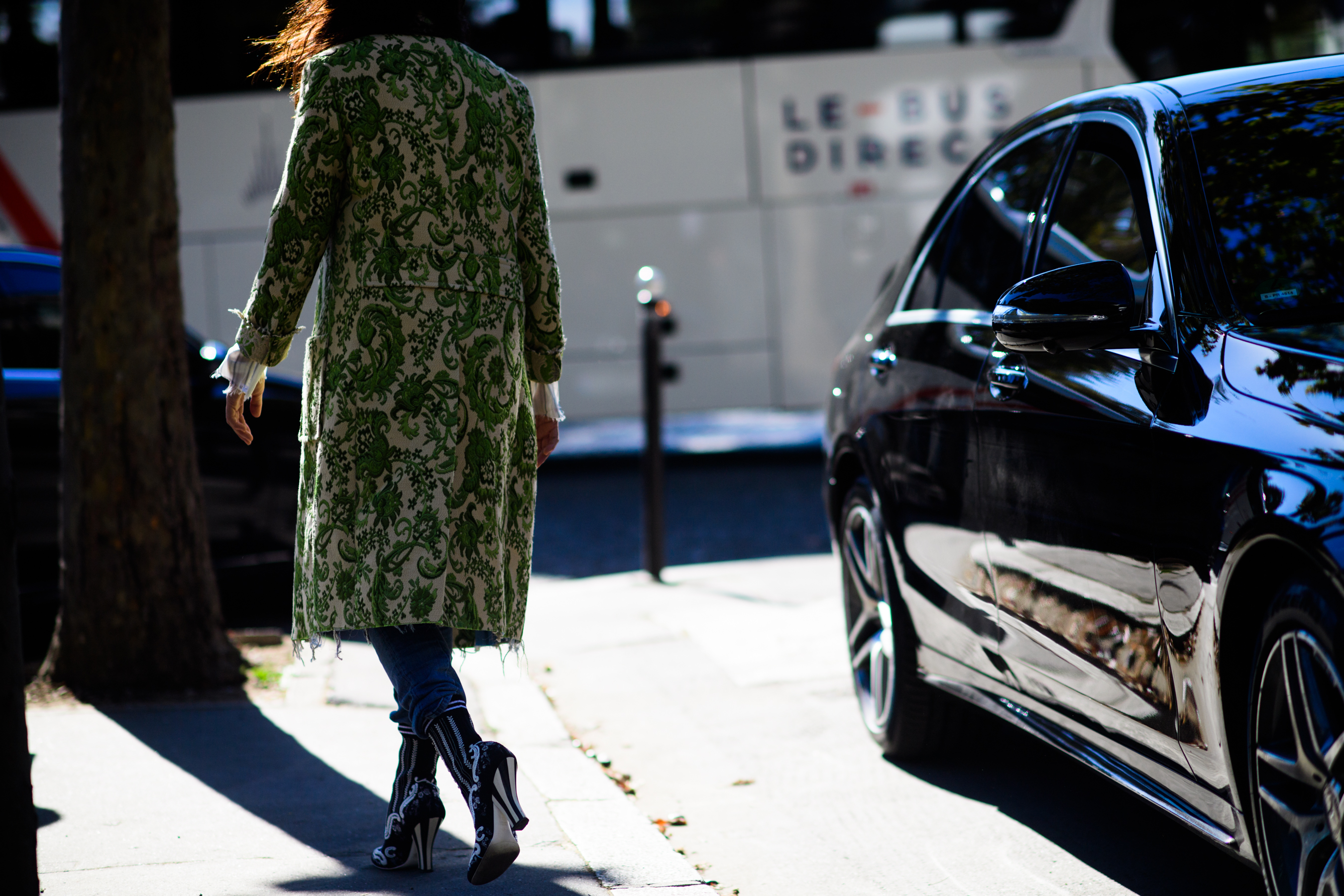 Woman in green coat walking in sunlight