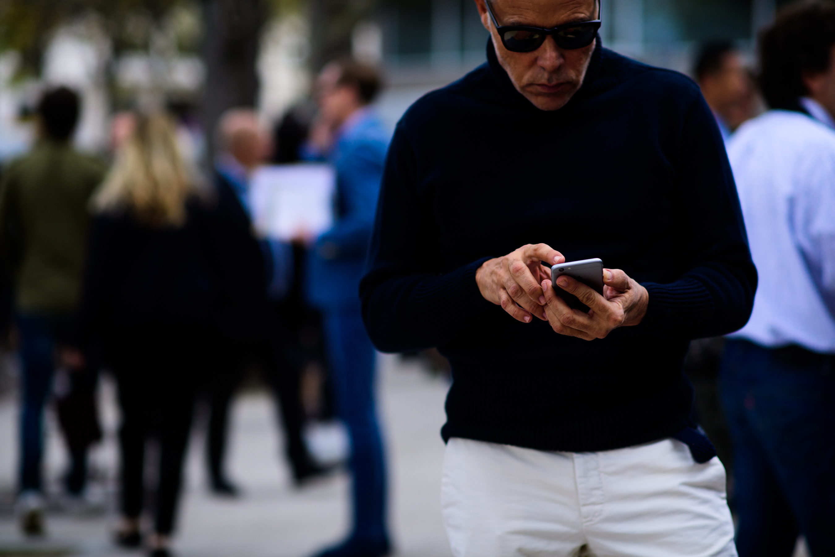 Stylist wearing navy knit sweater using phone