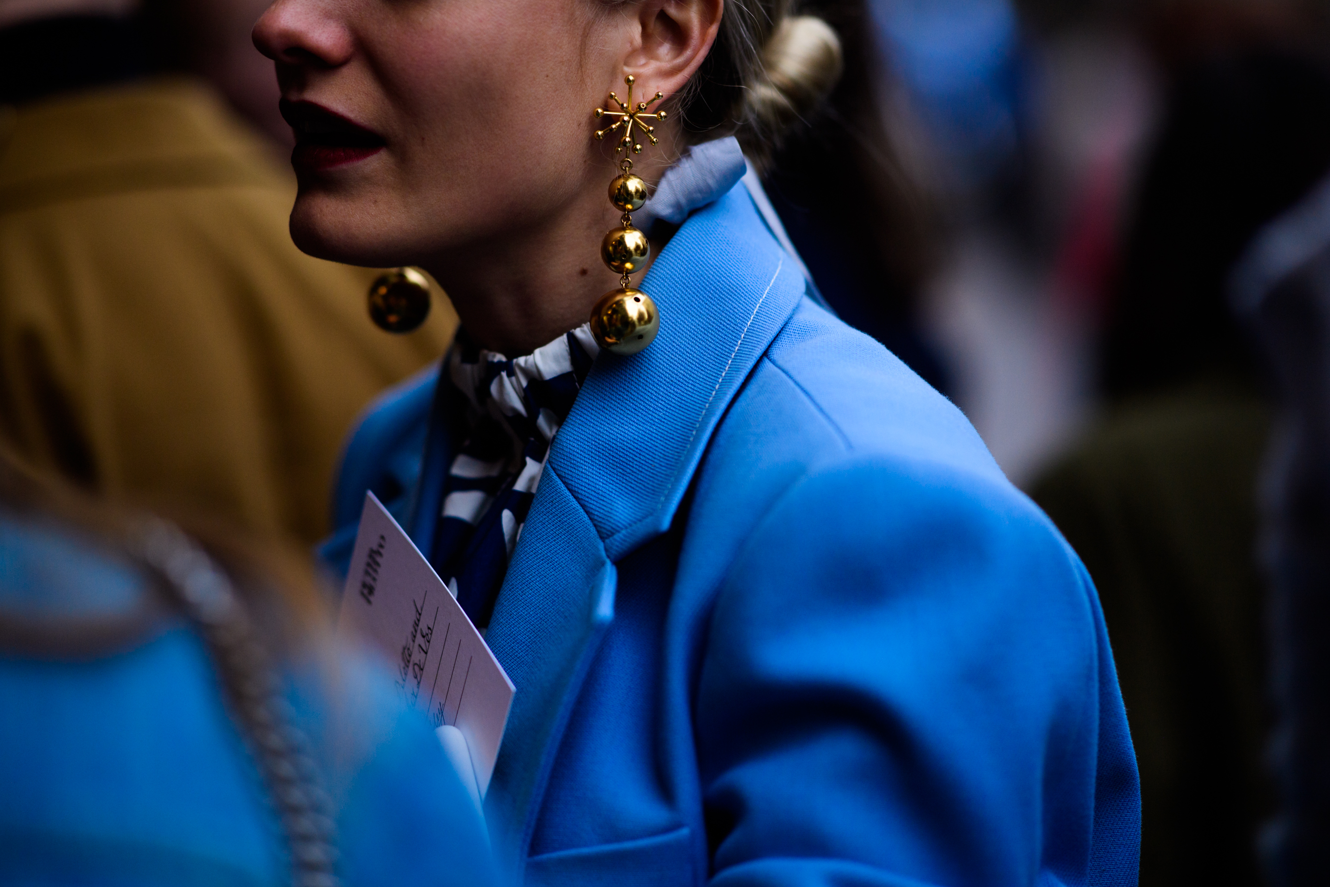 Woman wearing blue jacket and golden earrings