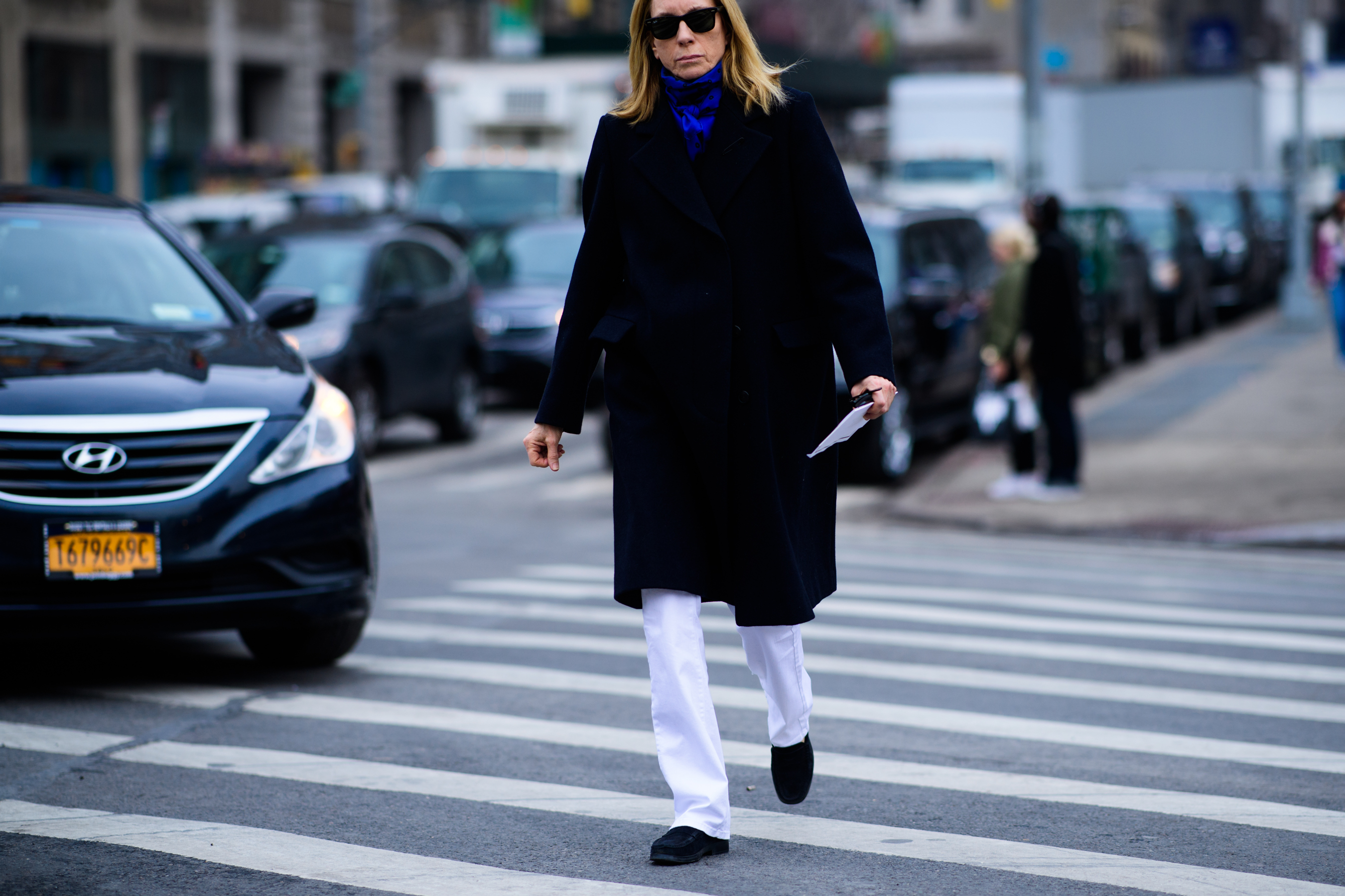 Woman wearing white pants and black coat
