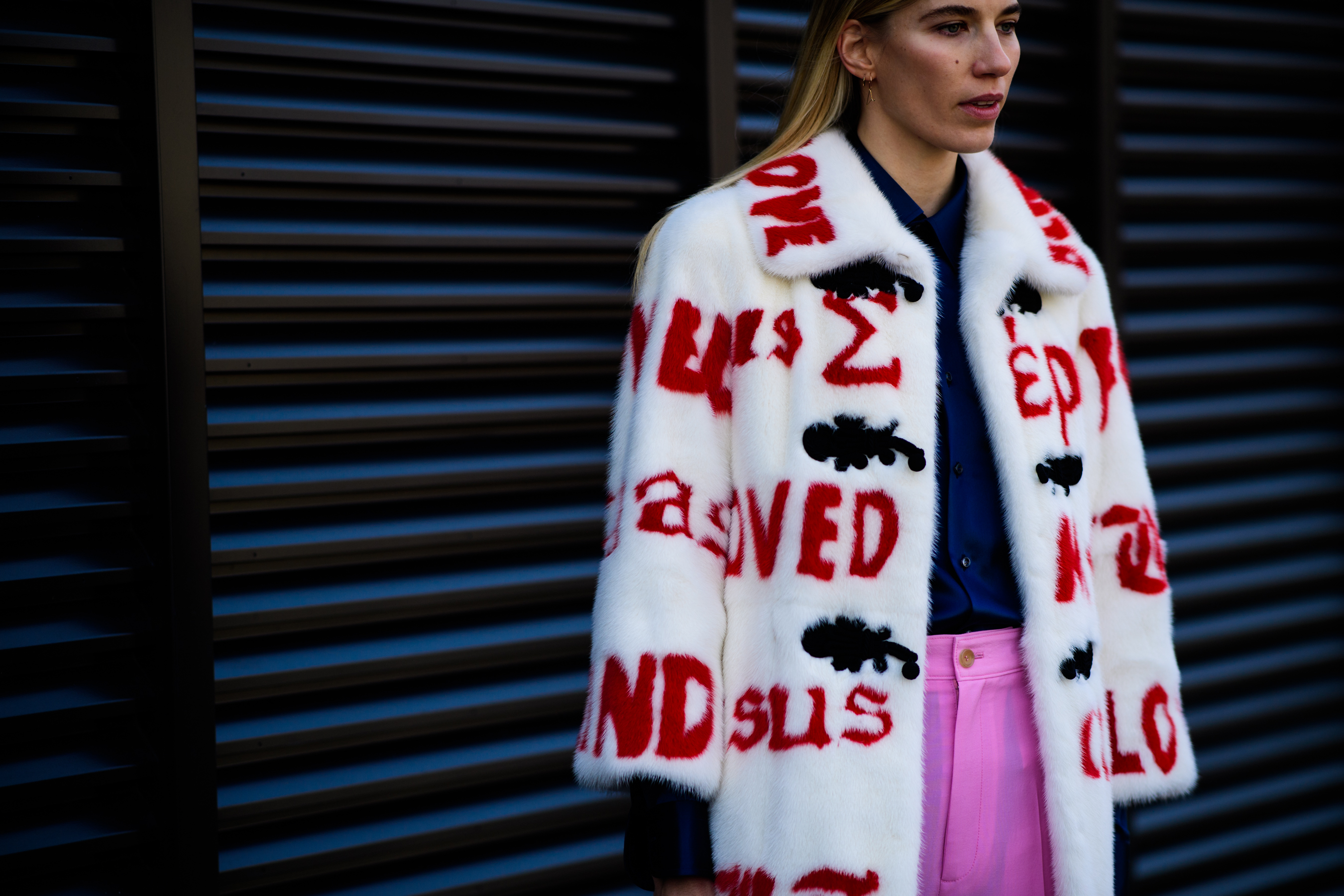 Woman wearing white coat with red texts
