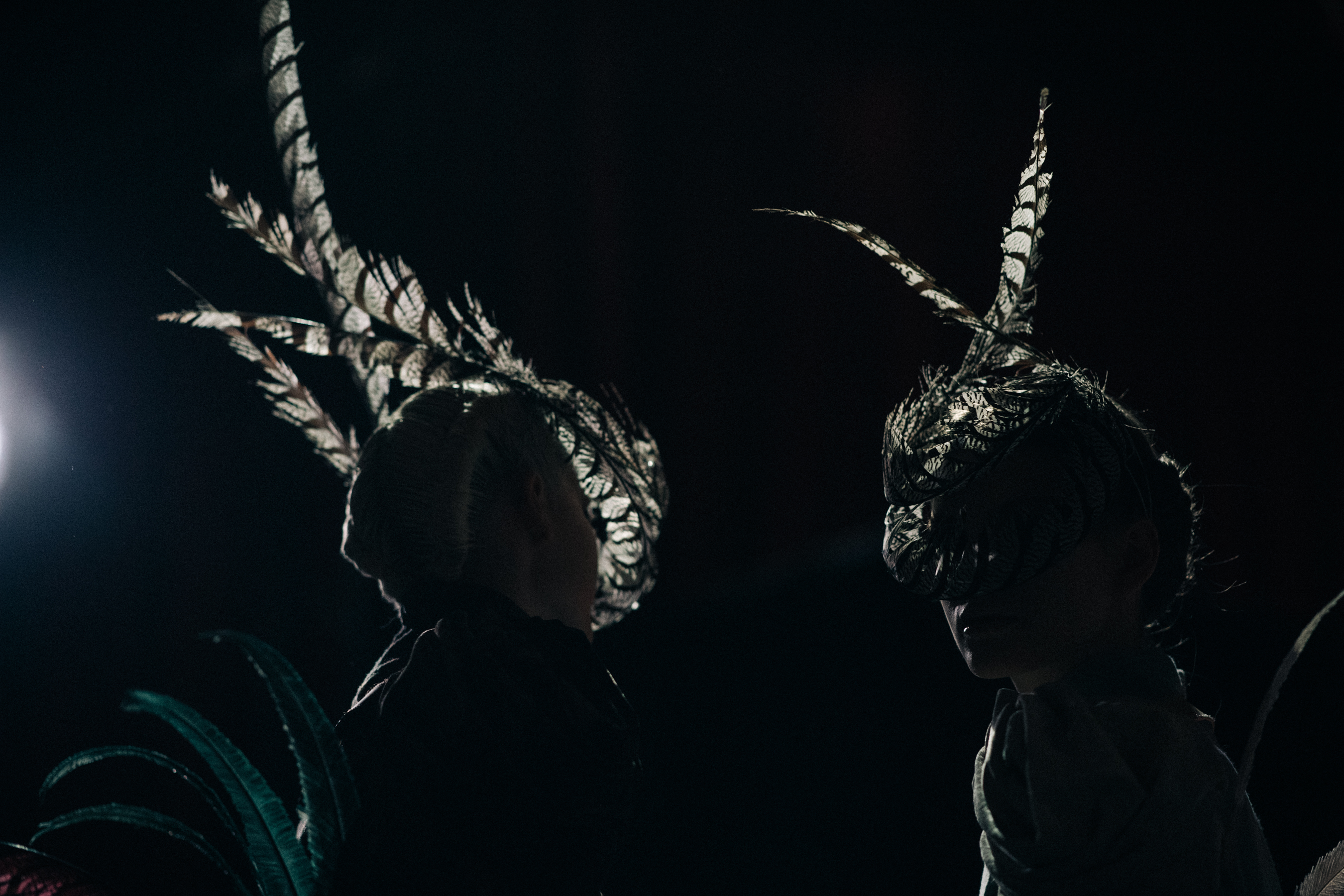 Two models wearing feather masks