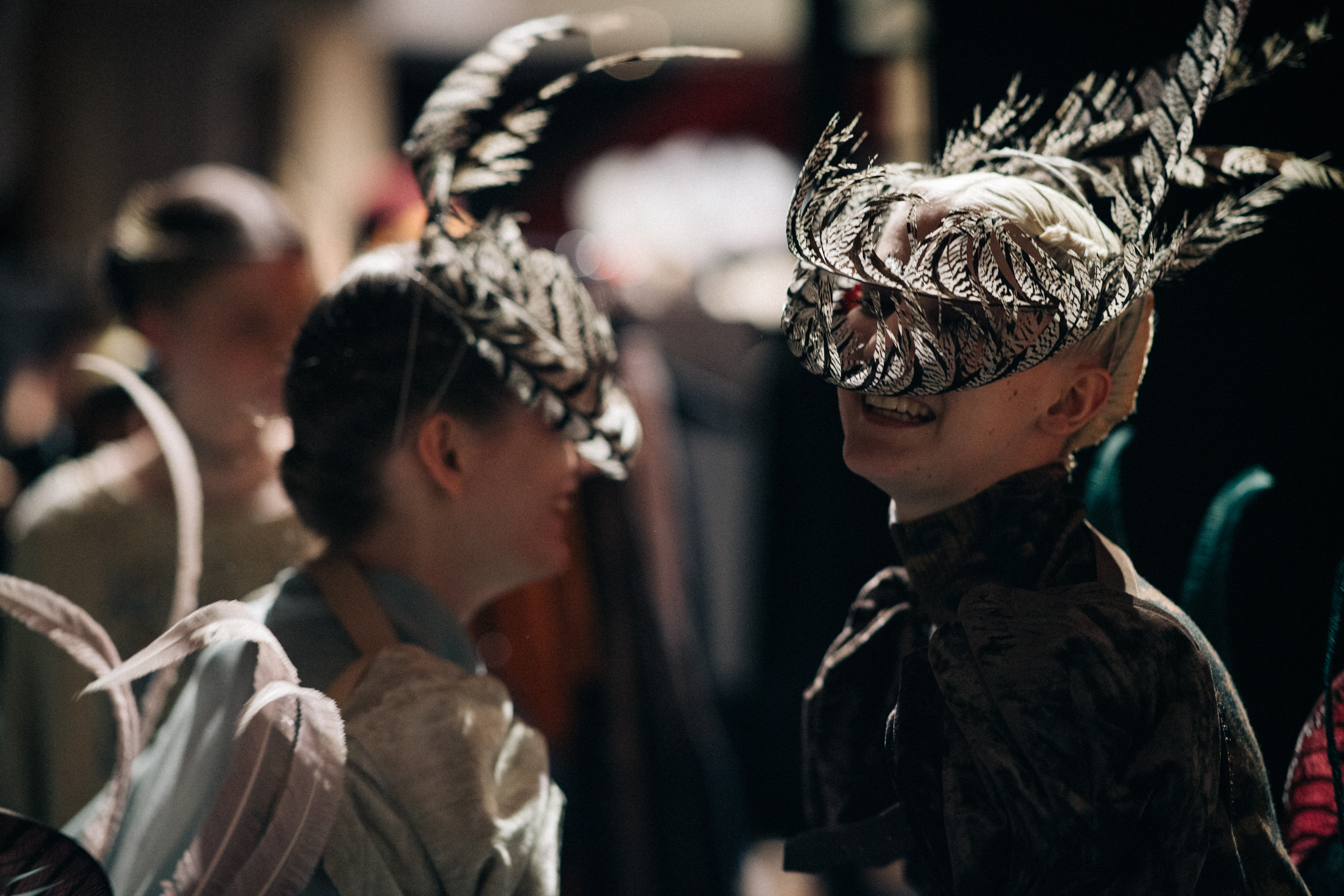 Models wearing feather masks
