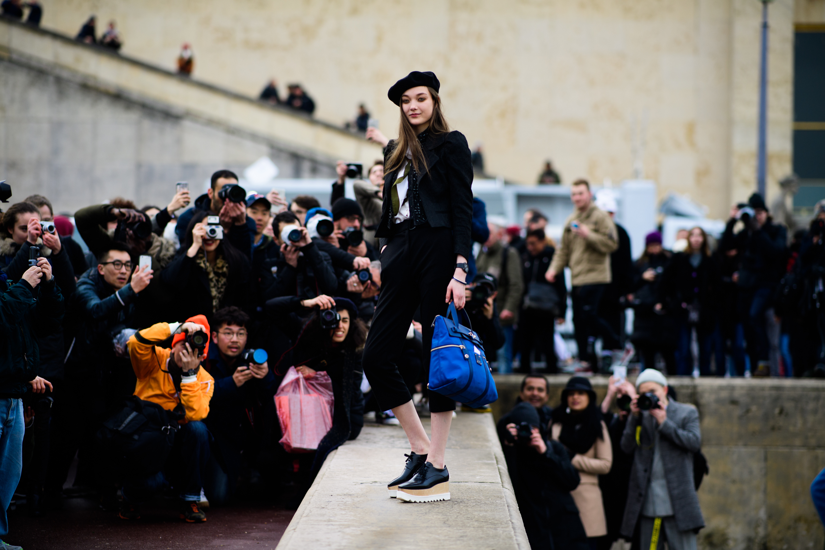 Model surrounded with street-style photographers