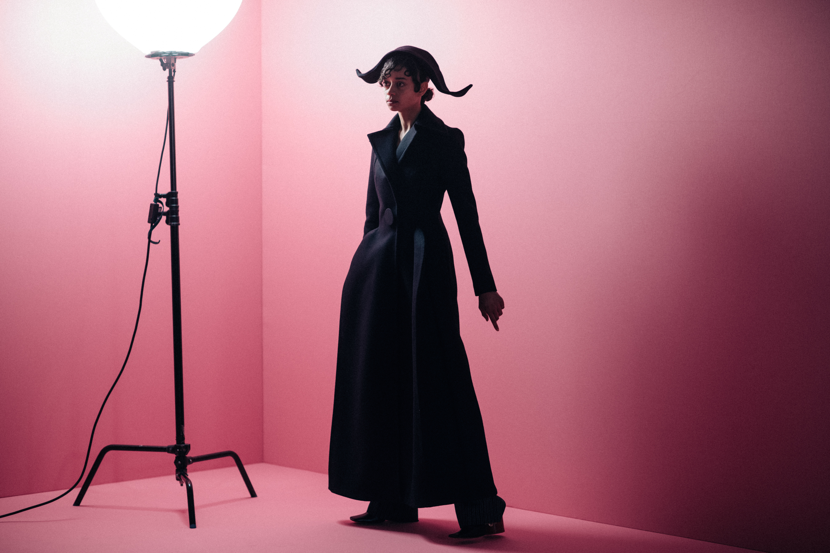 Girl staying against a pink wall