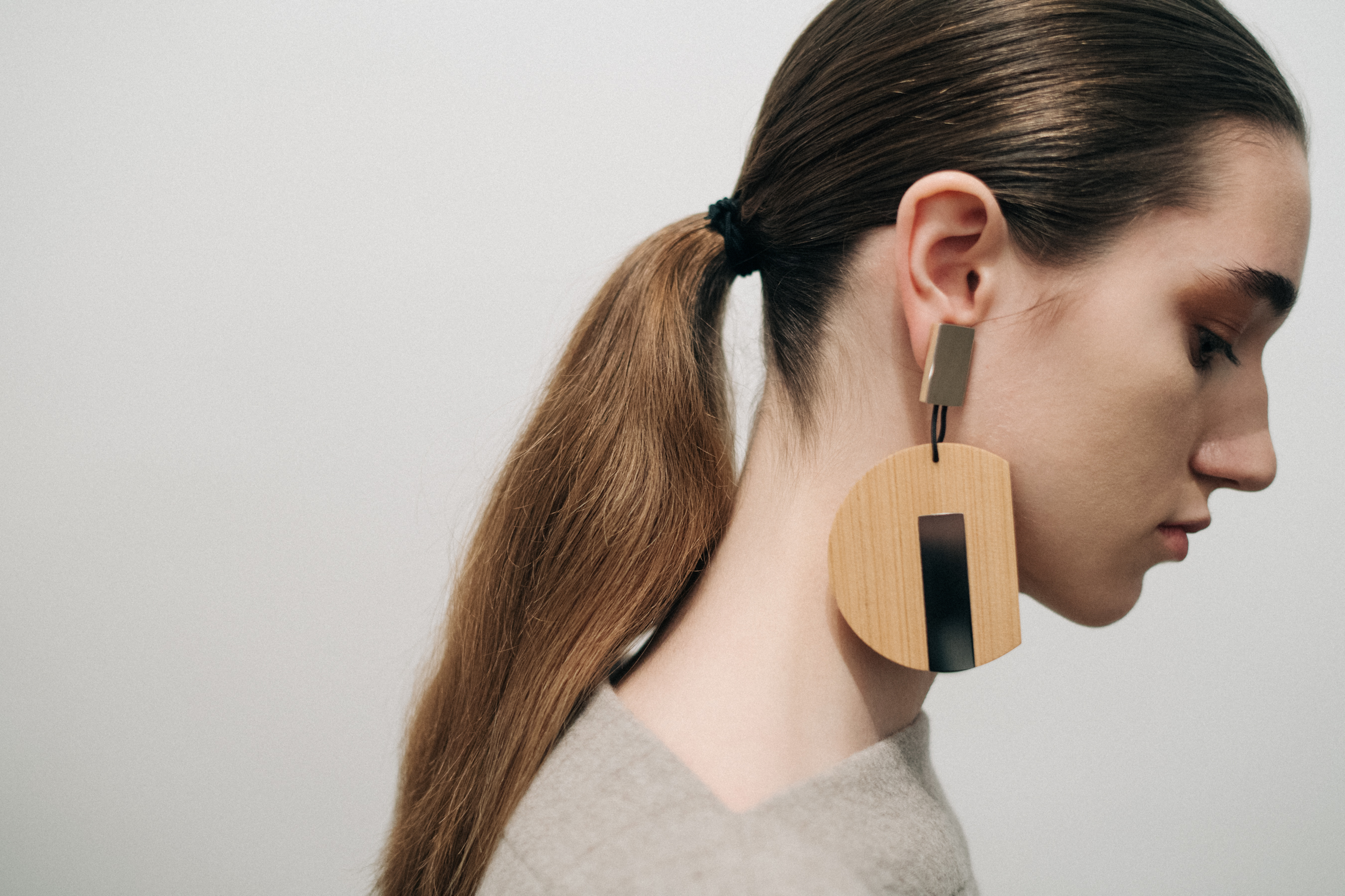 Model wearing oversized wooden earrings