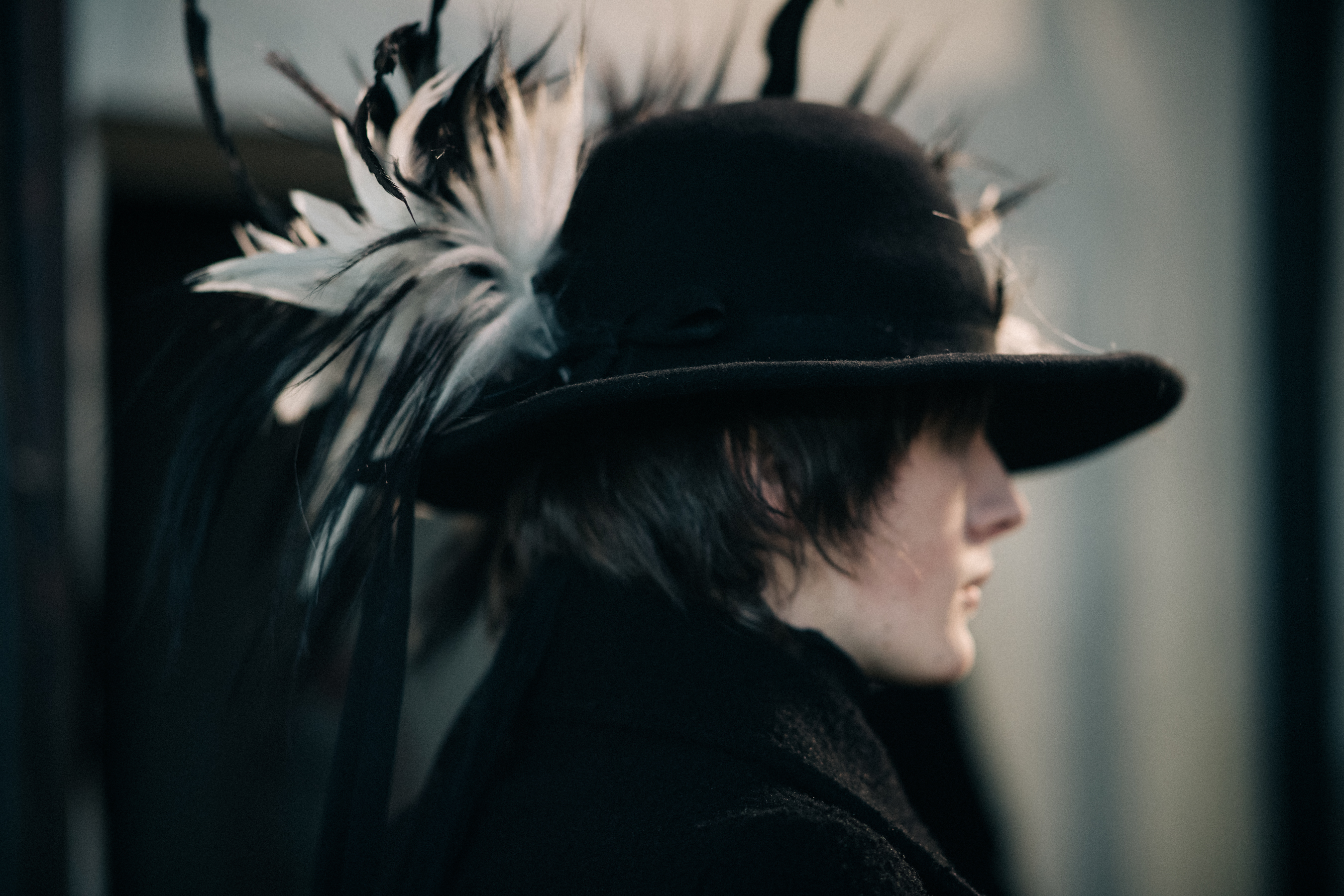 Male model wearing black hat with feathers