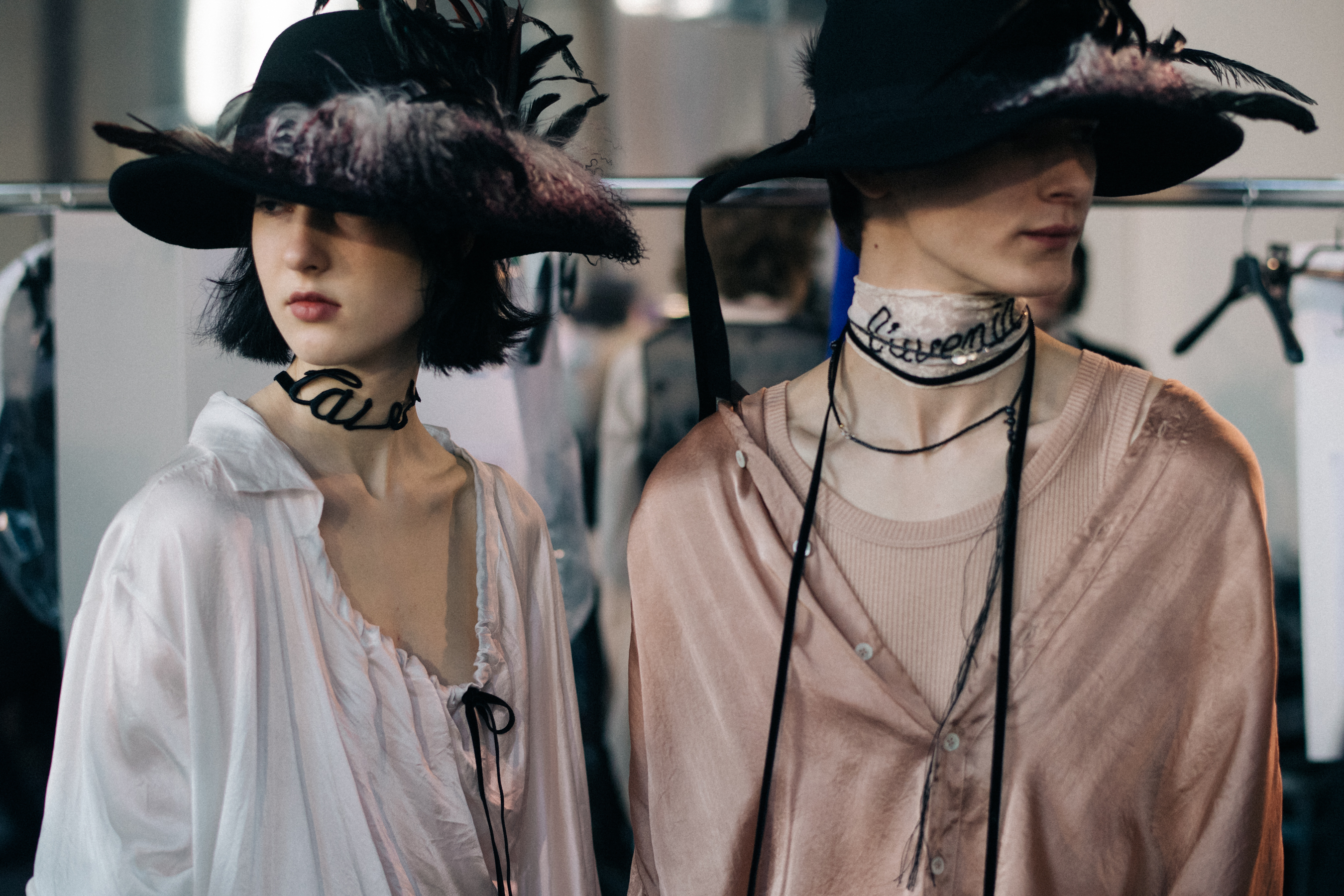 Two models wearing feather hats