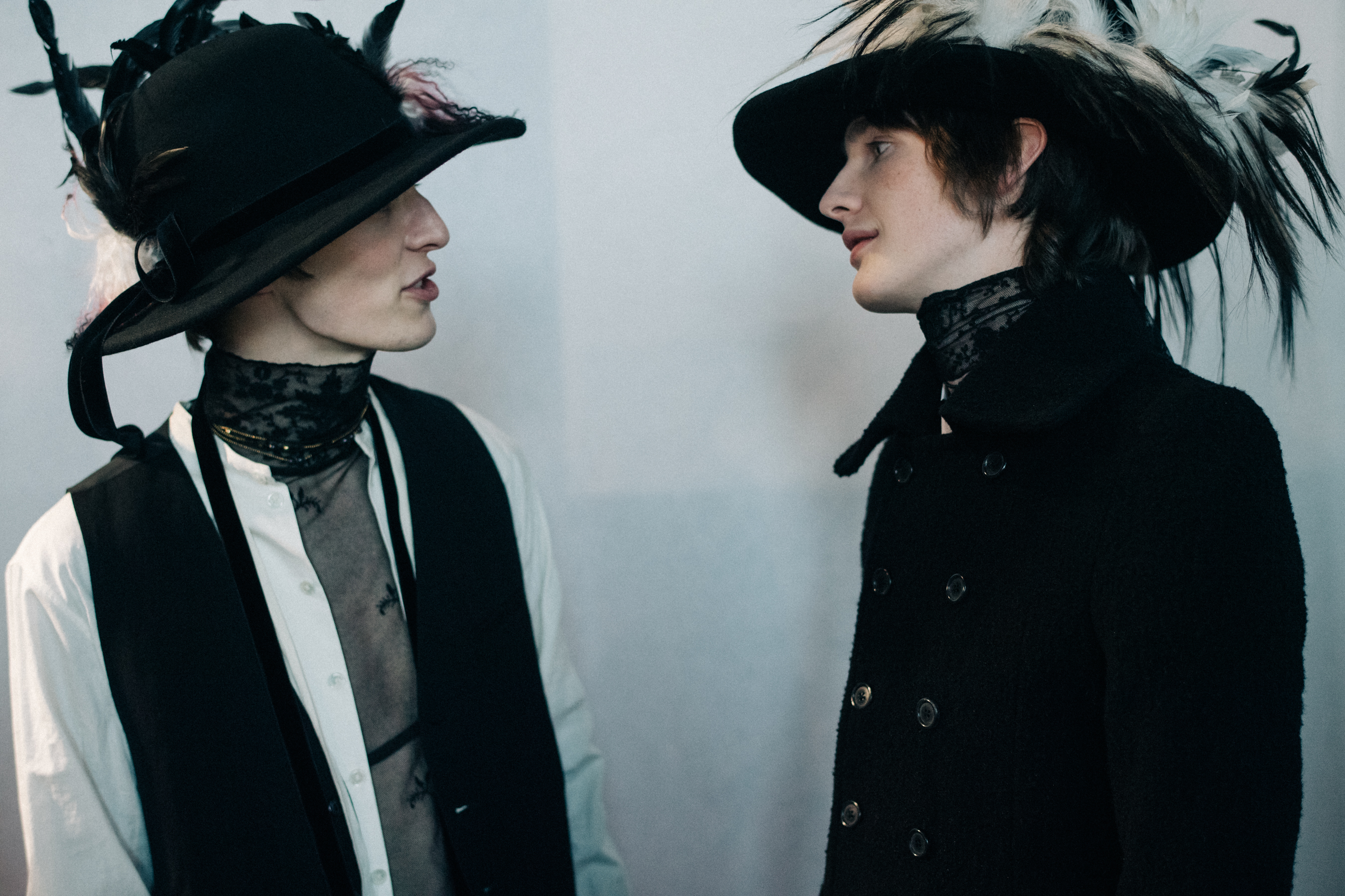 Male models wearing feather hats