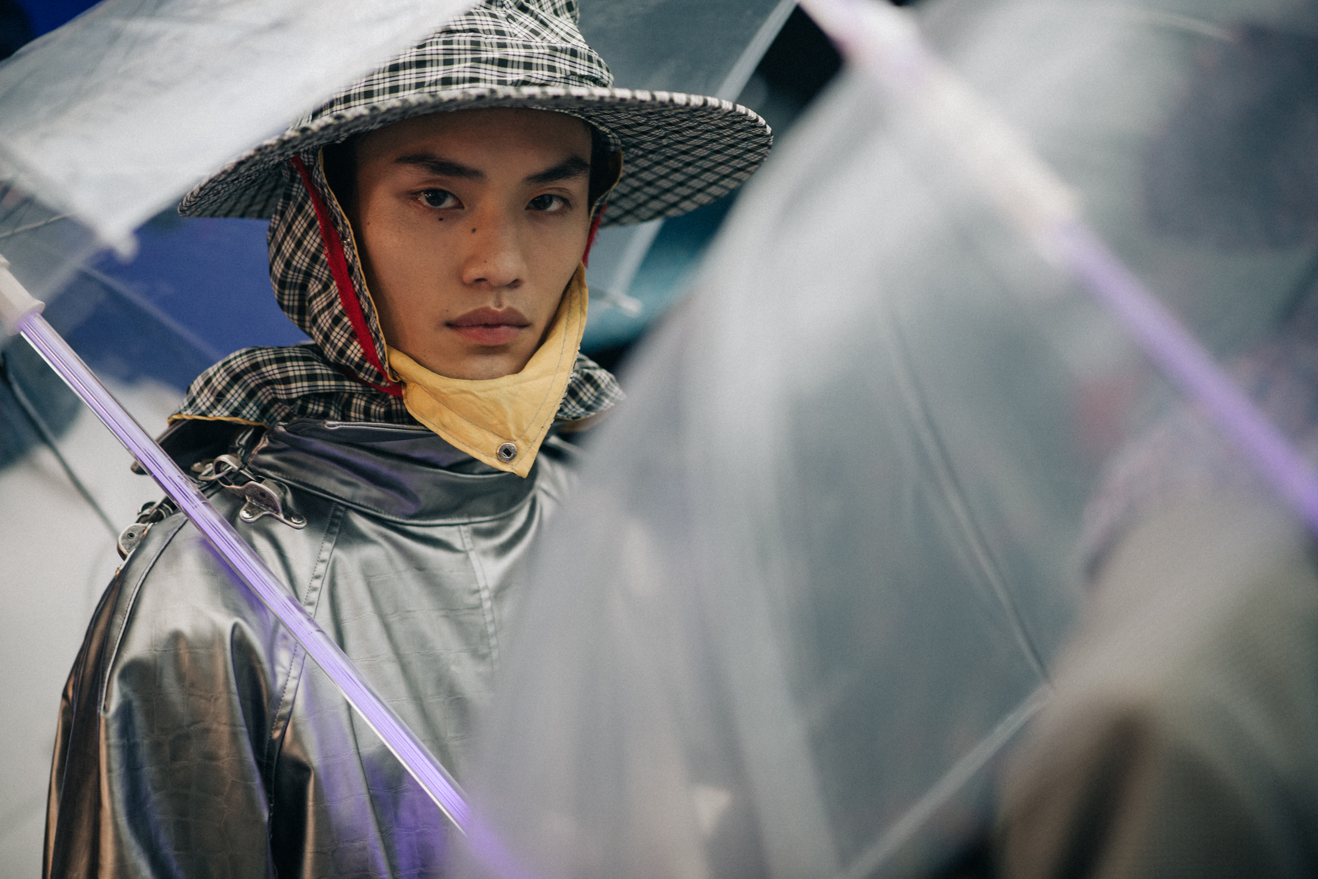 Male models wearing rain hats and umbrellas