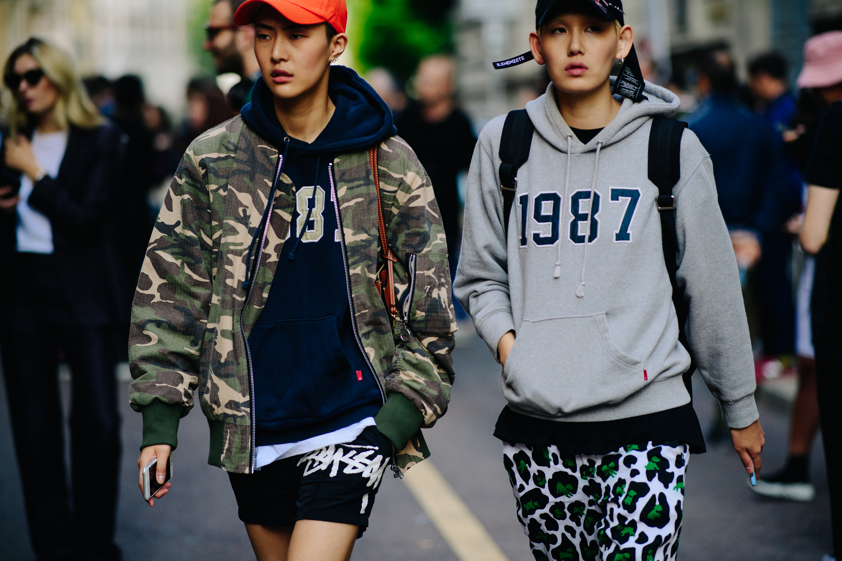 Two Asian models wearing graphic hoodies and camouflage