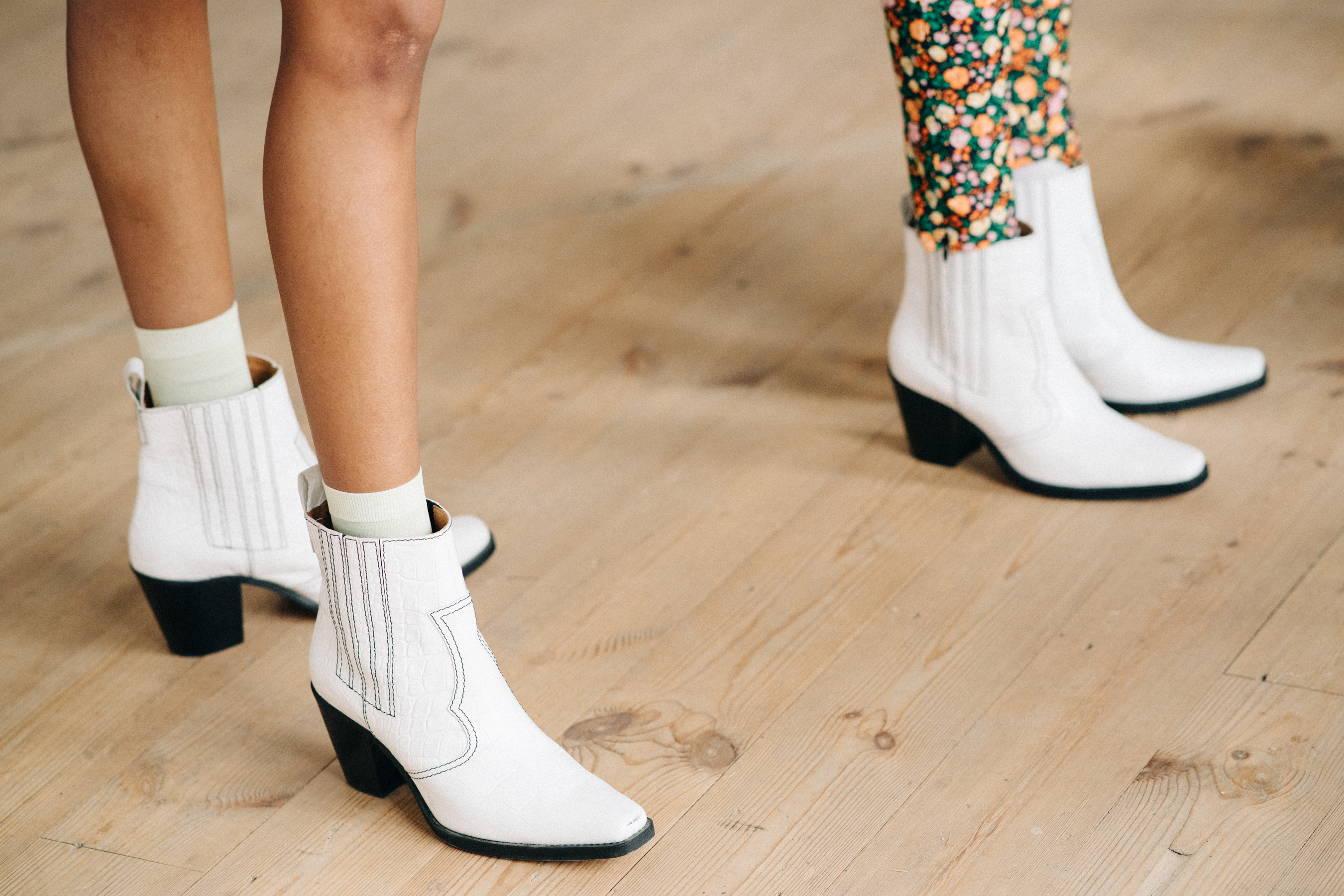 Two models wearing white boots