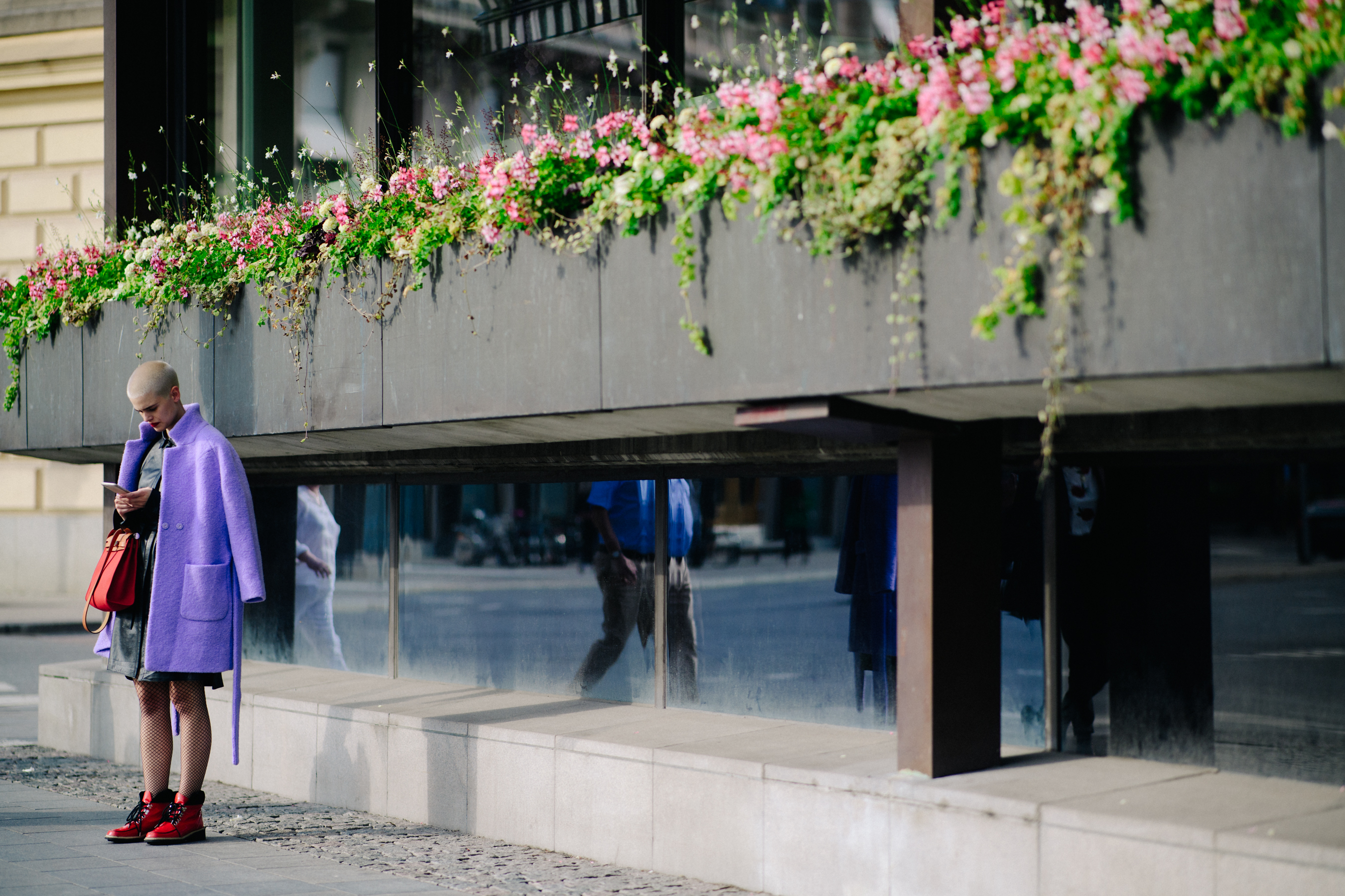 Model wearing lavender coat and red handbag