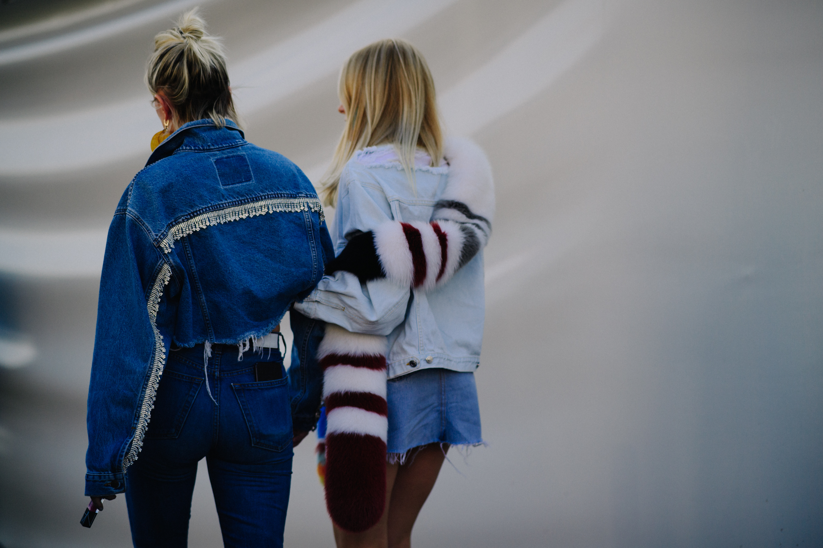 Two women linking arms wearing denim