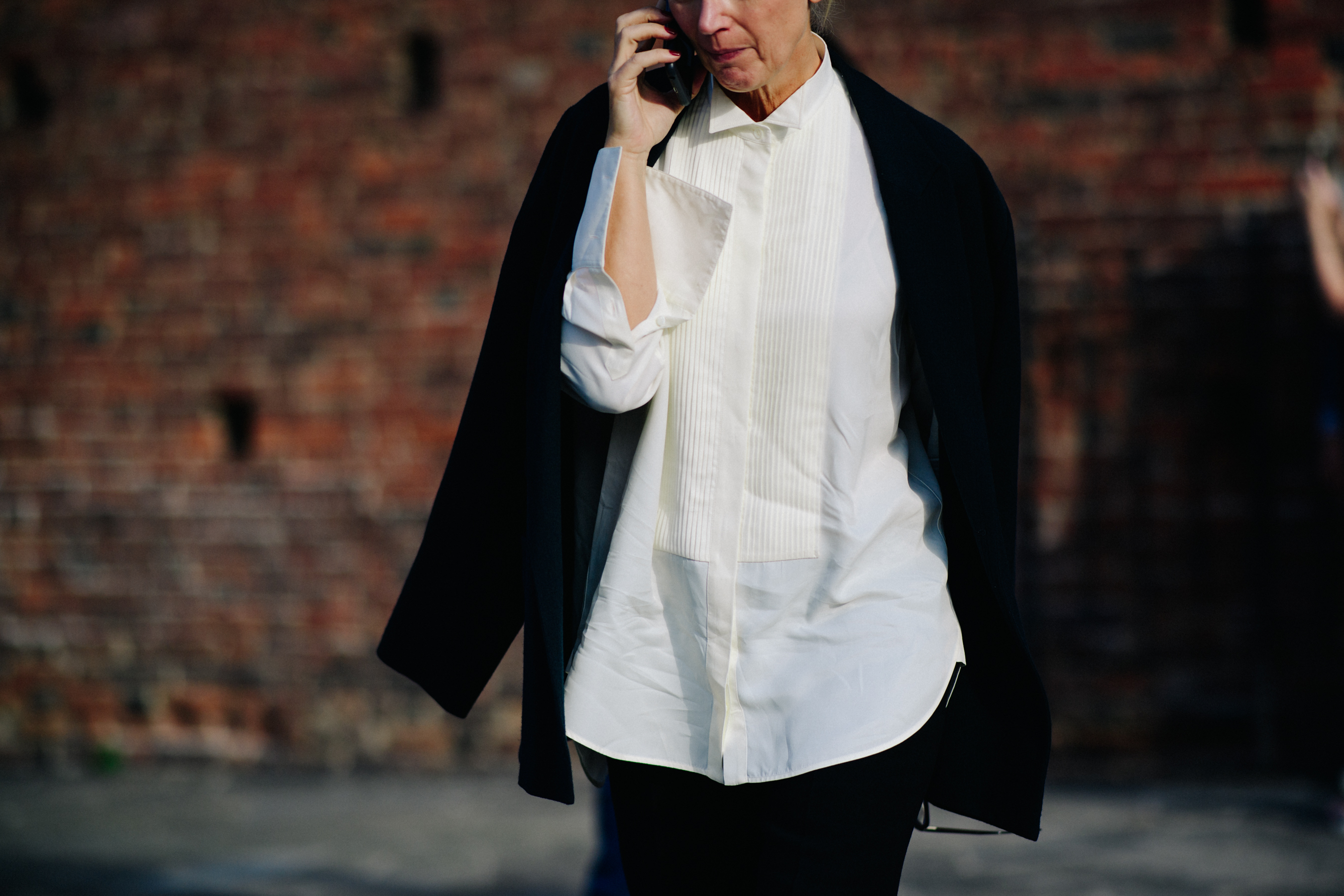 Woman on phone with black suit jacket around her shoulders