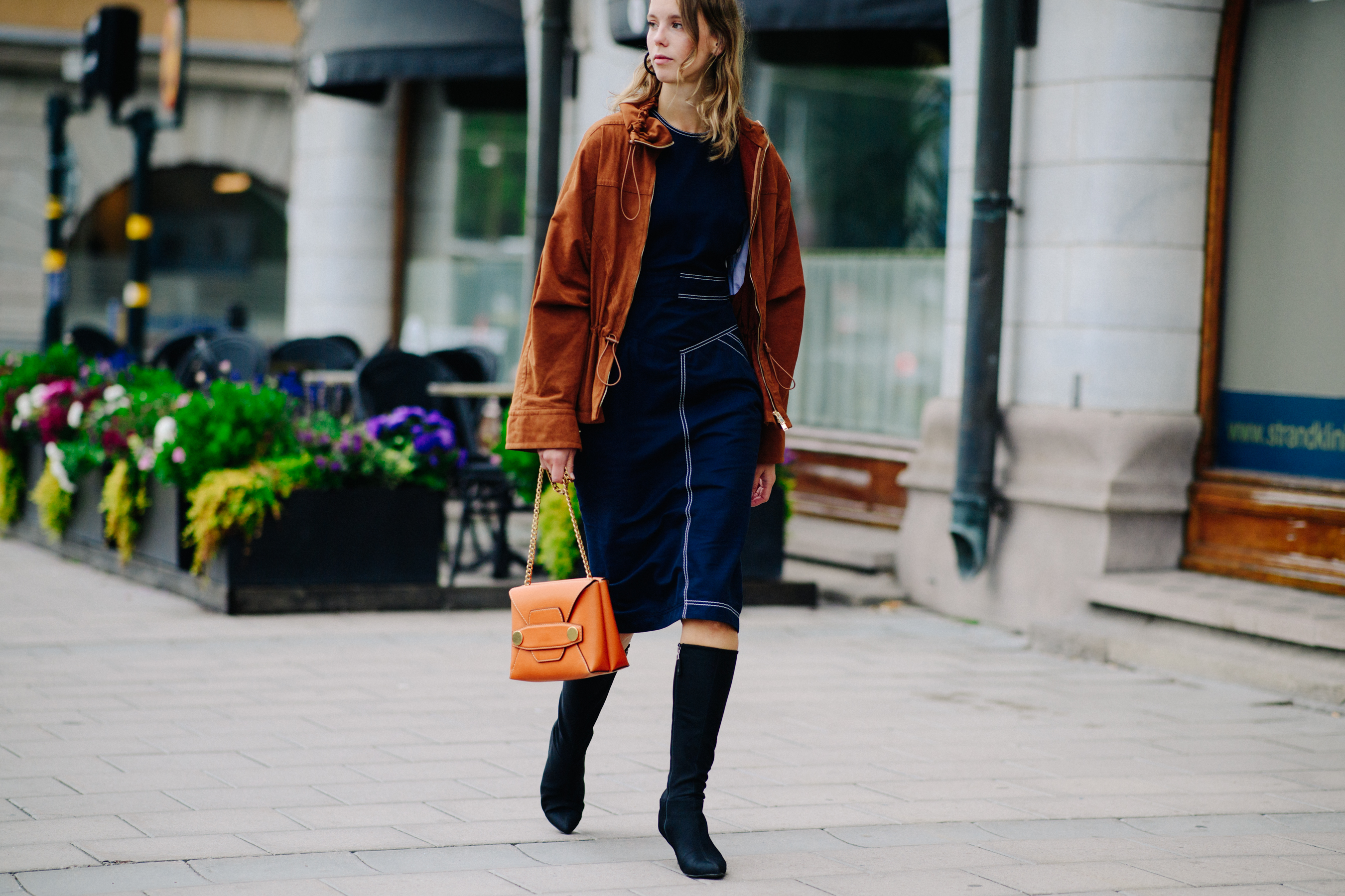 Woman wearing denim skirt and orange handbag