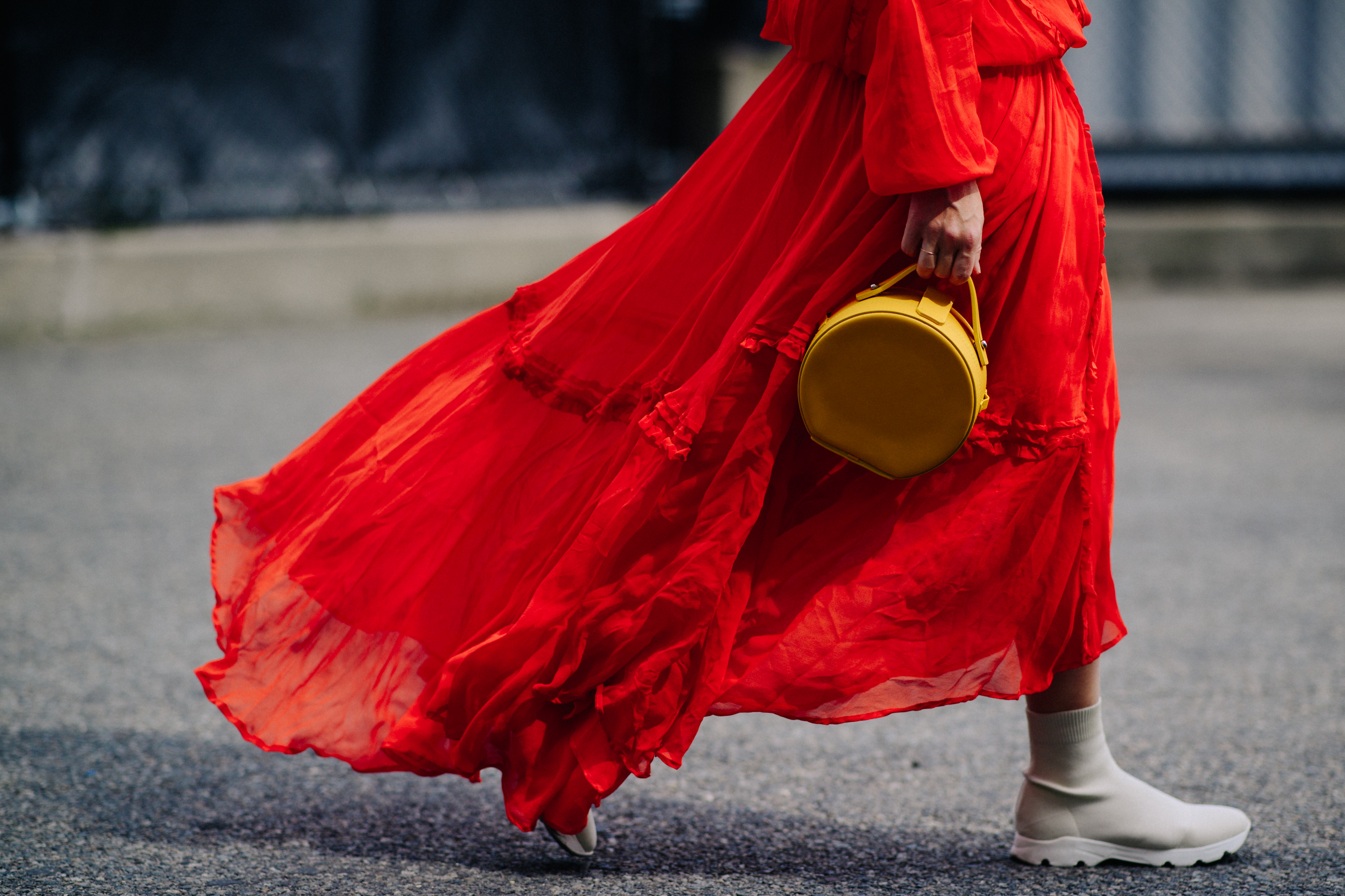 Woman wearing long red dress and yellow bag