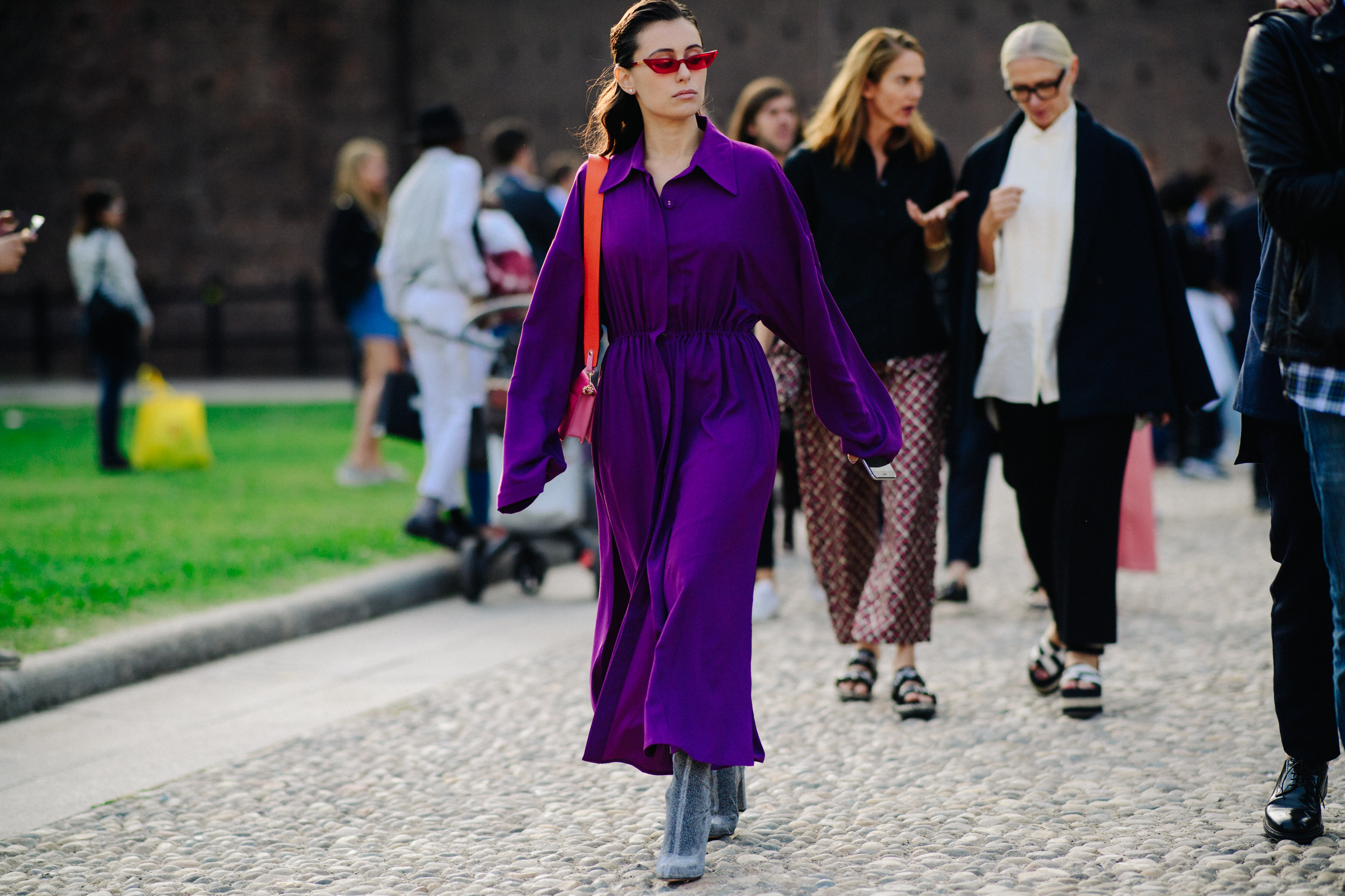 Woman walking in purple outfit with orange bag