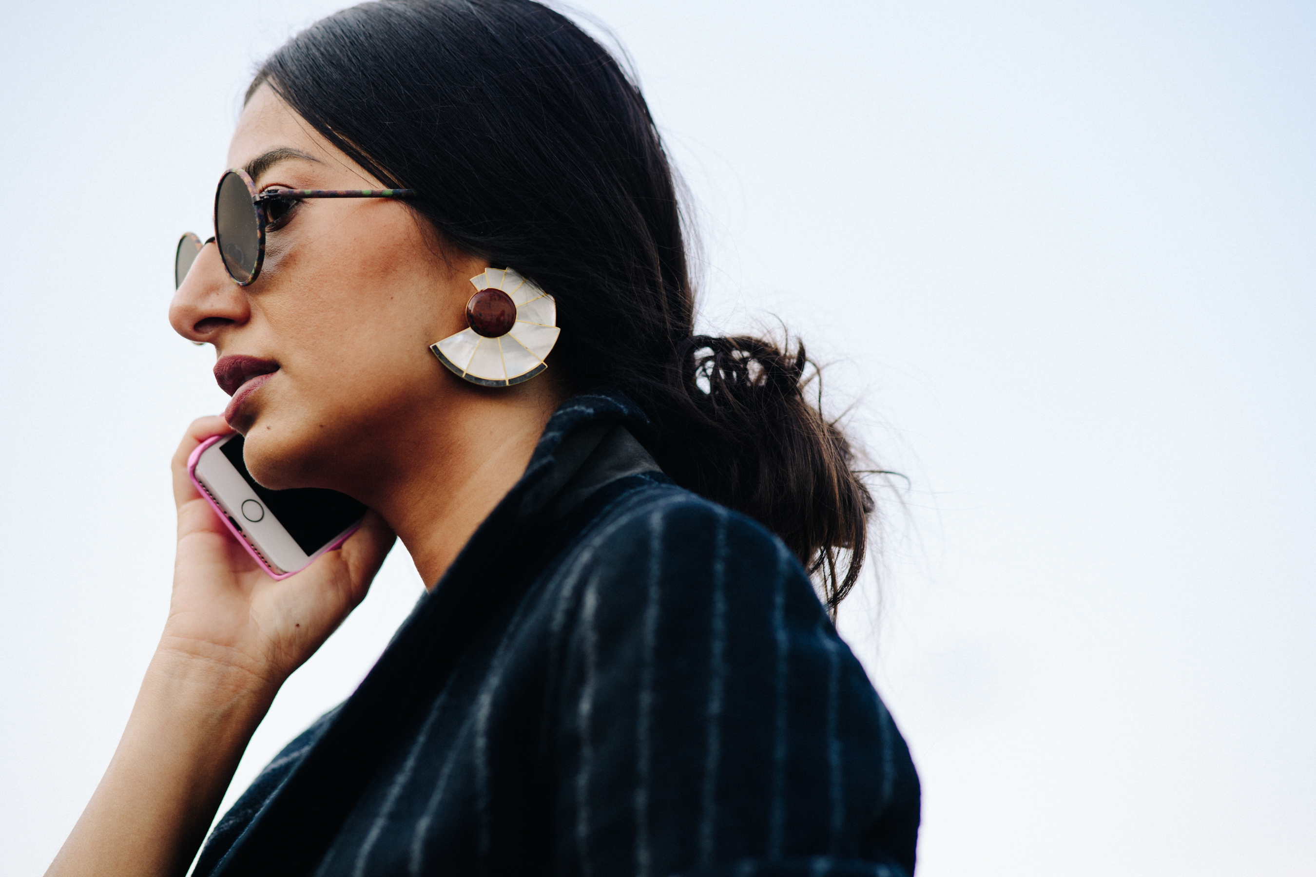 Closeup of woman wearing round sunglasses and earrings