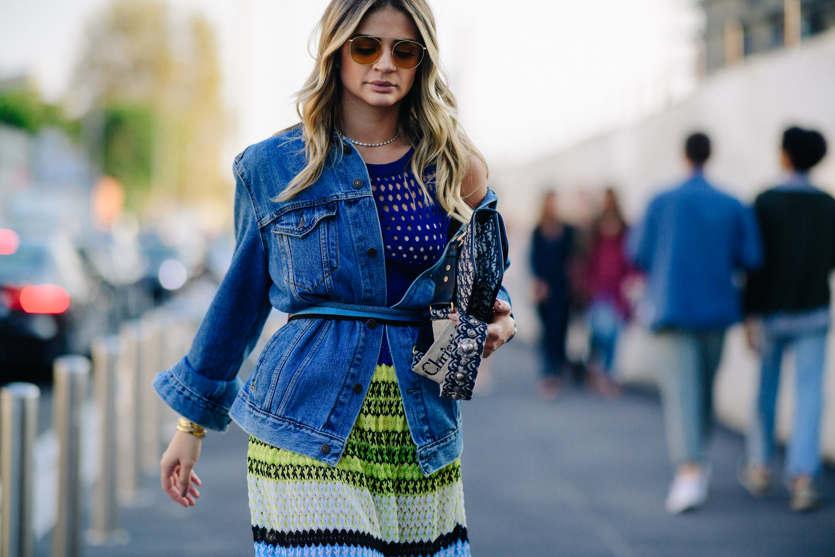 Woman walking in denim jacket belted over dress